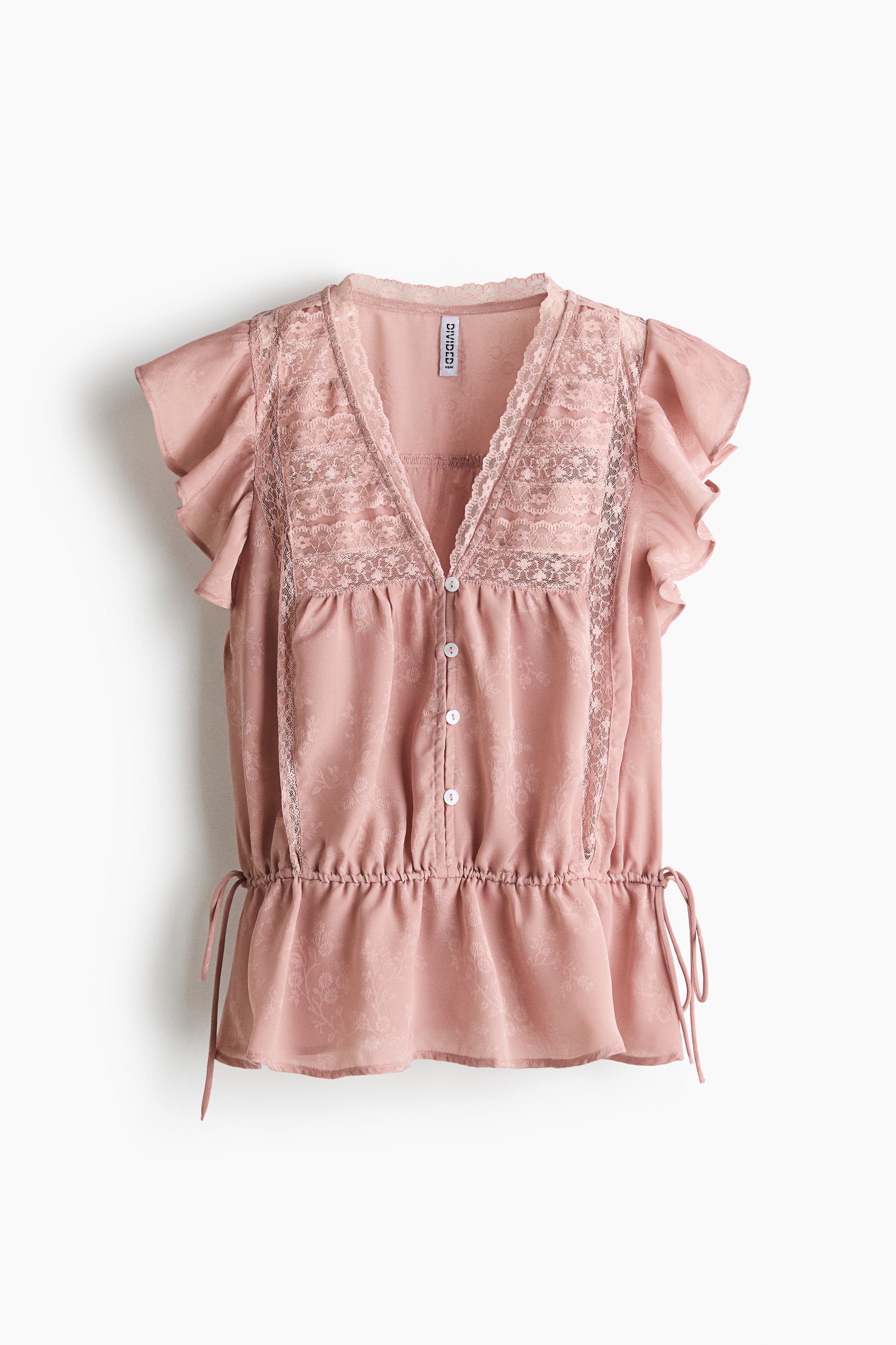 The model is wearing a pink, sheer-weave blouse featuring a lace-trimmed V-neckline, flutter sleeves, and a gathered drawstring waist, paired with blue denim jeans.