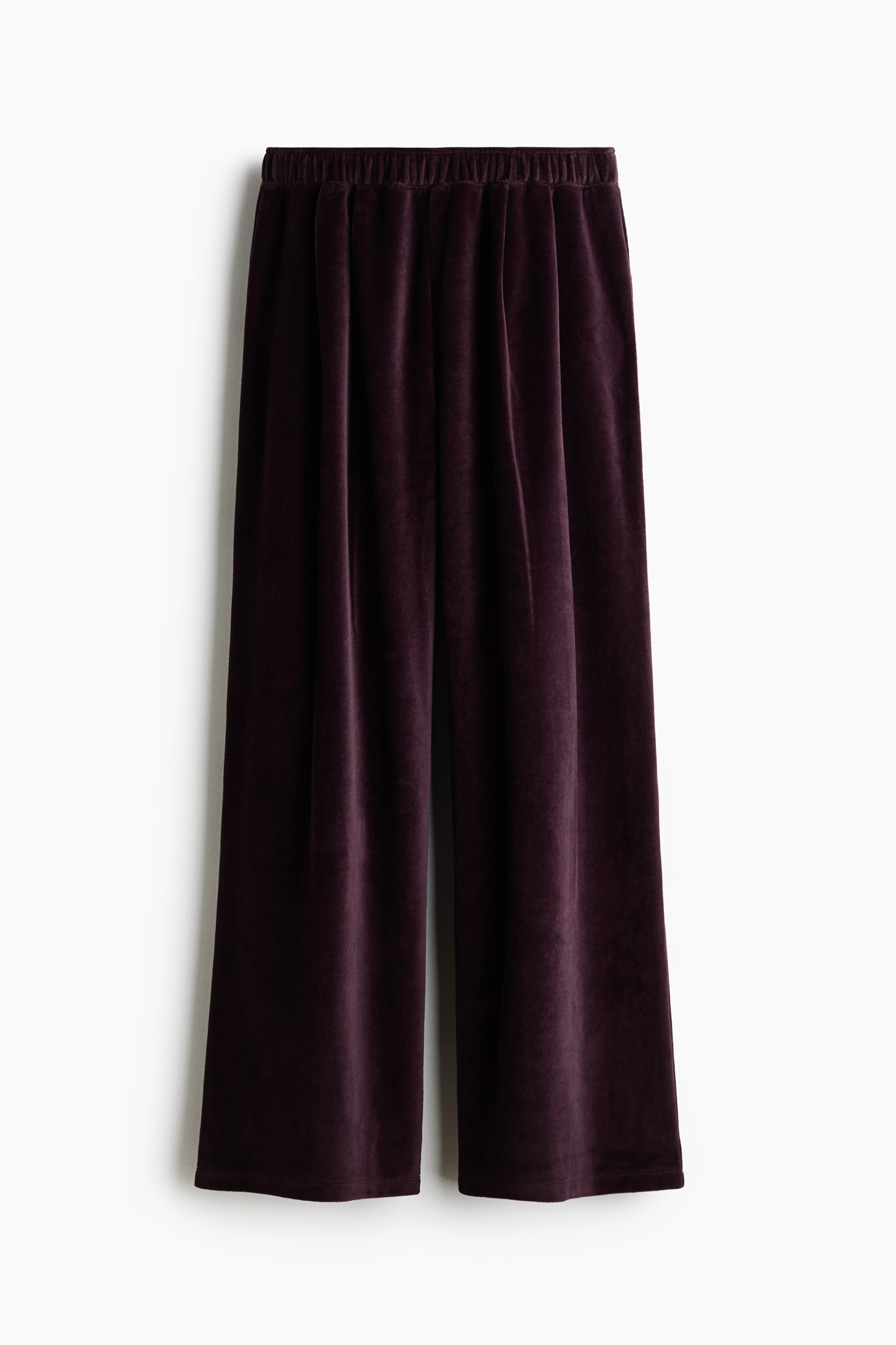View larger image: The dark purple velvet pants are hanging flat, showcasing an elastic waistband with gathers and a wide-leg silhouette.