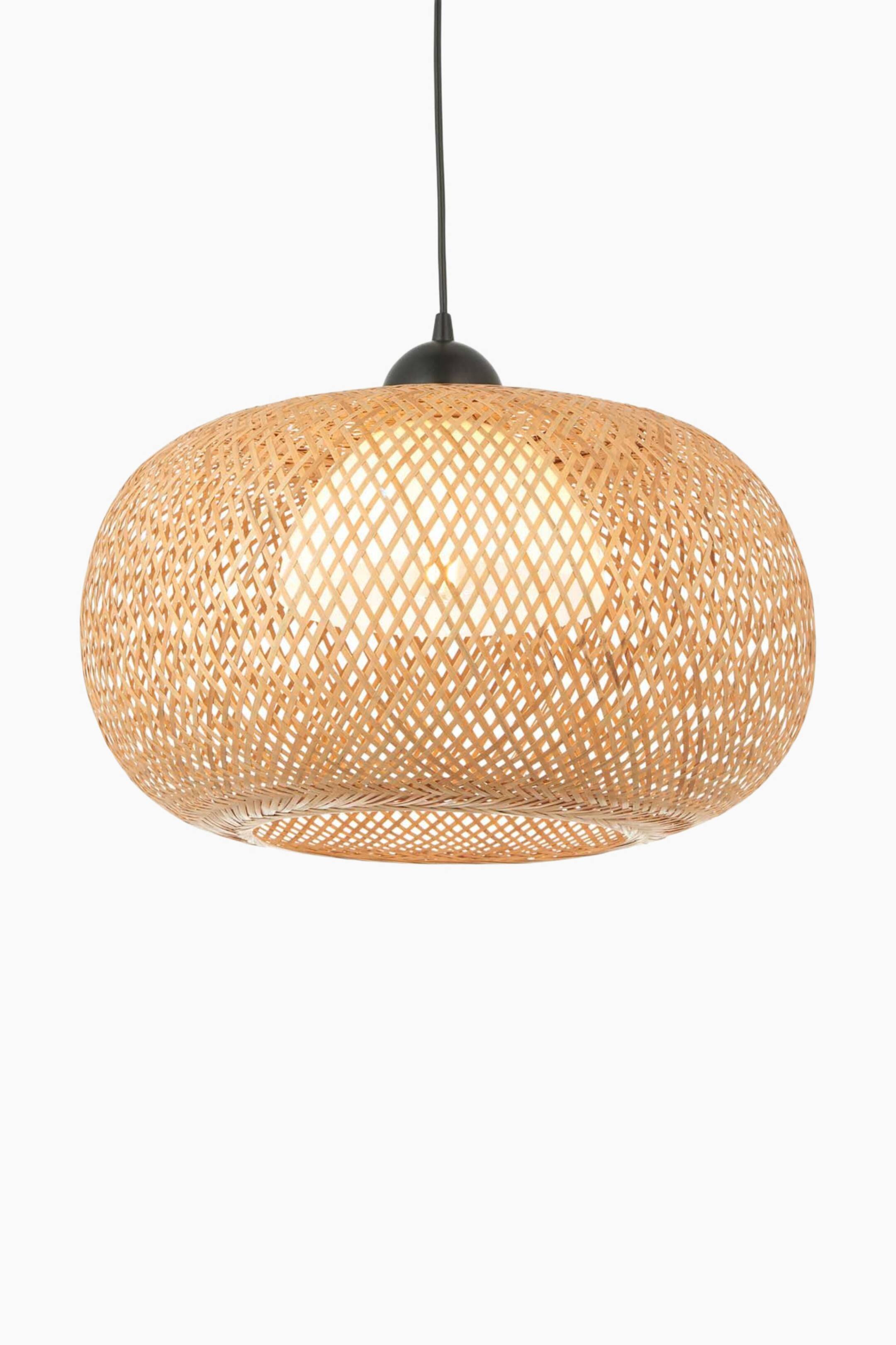 View larger image: A pendant light is hanging, featuring an oval-shaped shade woven from light-coloured bamboo or rattan. The shade is displaying a diamond lattice weave pattern, with a glowing light bulb visible inside, and is attached to a black suspension cord and cap.