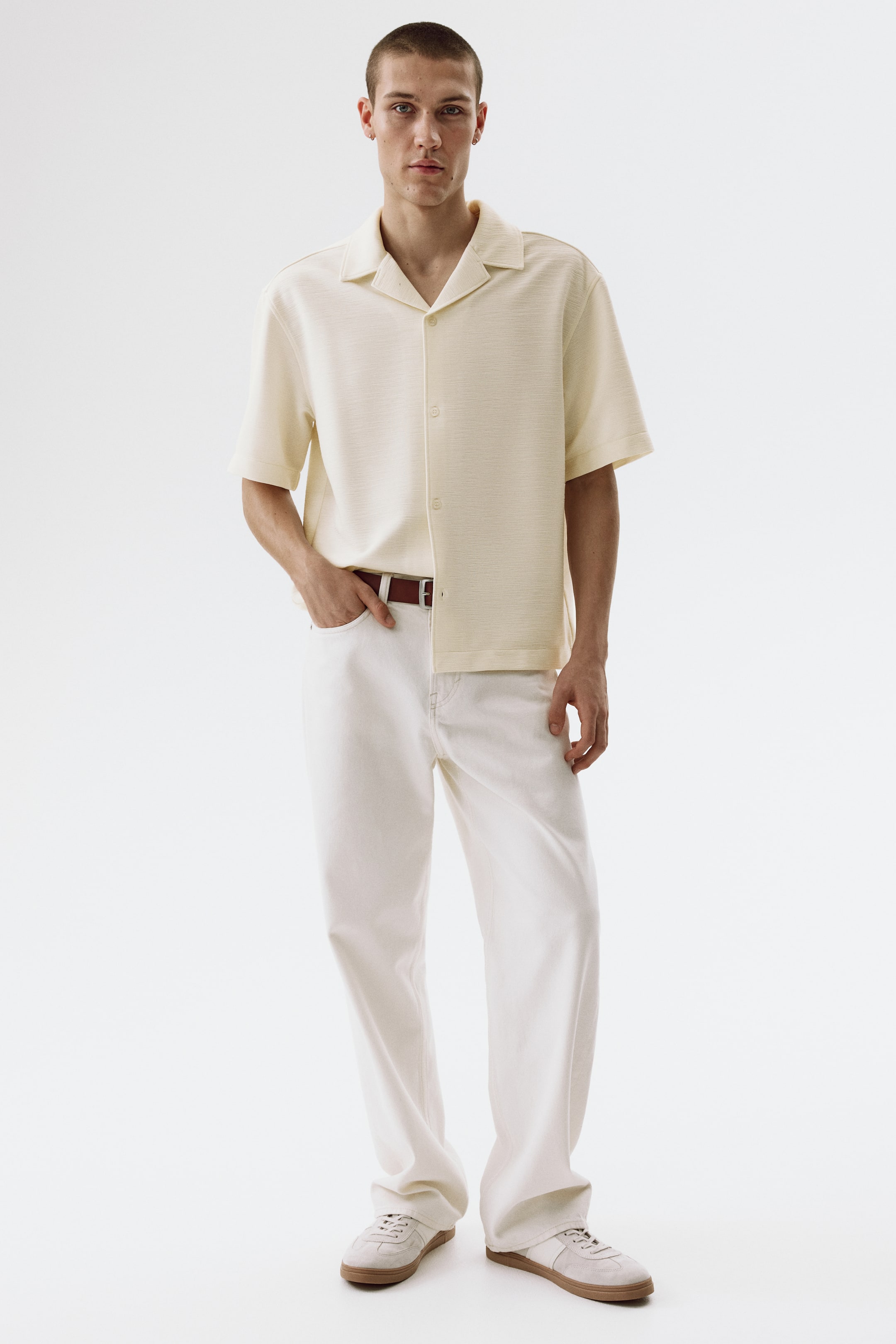View larger image: A light yellow short-sleeved shirt featuring a camp collar, a button-up front with light-coloured buttons, and a subtle textured weave. It is designed with a relaxed fit and is facing forward.