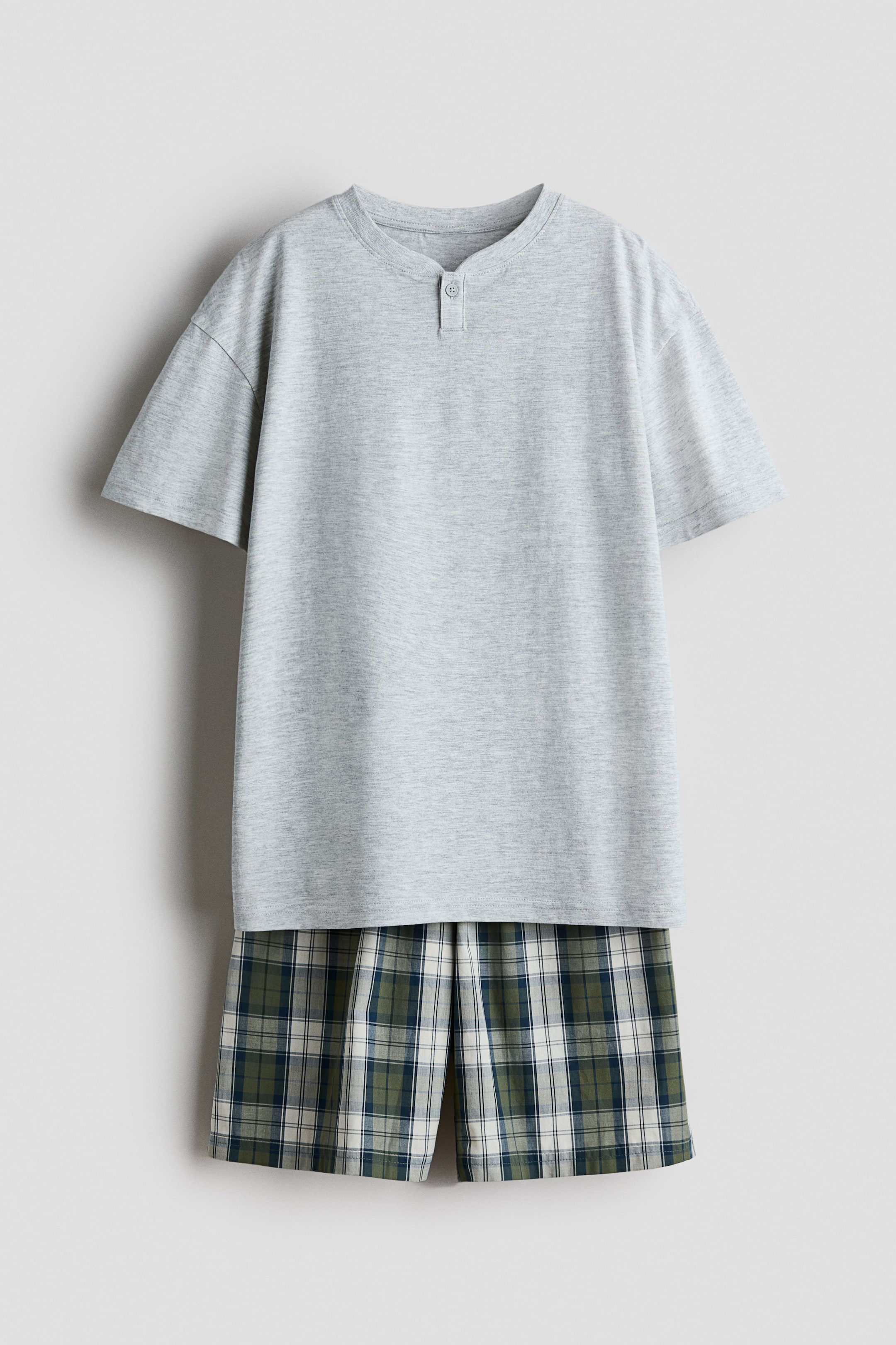 Agrandir l'image: Pyjama composé d'un T-shirt gris clair chiné, présentant un col rond avec bordure côtelée, une patte de boutonnage henley à deux boutons et des épaules tombantes, assorti à un short à carreaux affichant un motif vert, bleu et crème et une taille élastiquée recouverte.