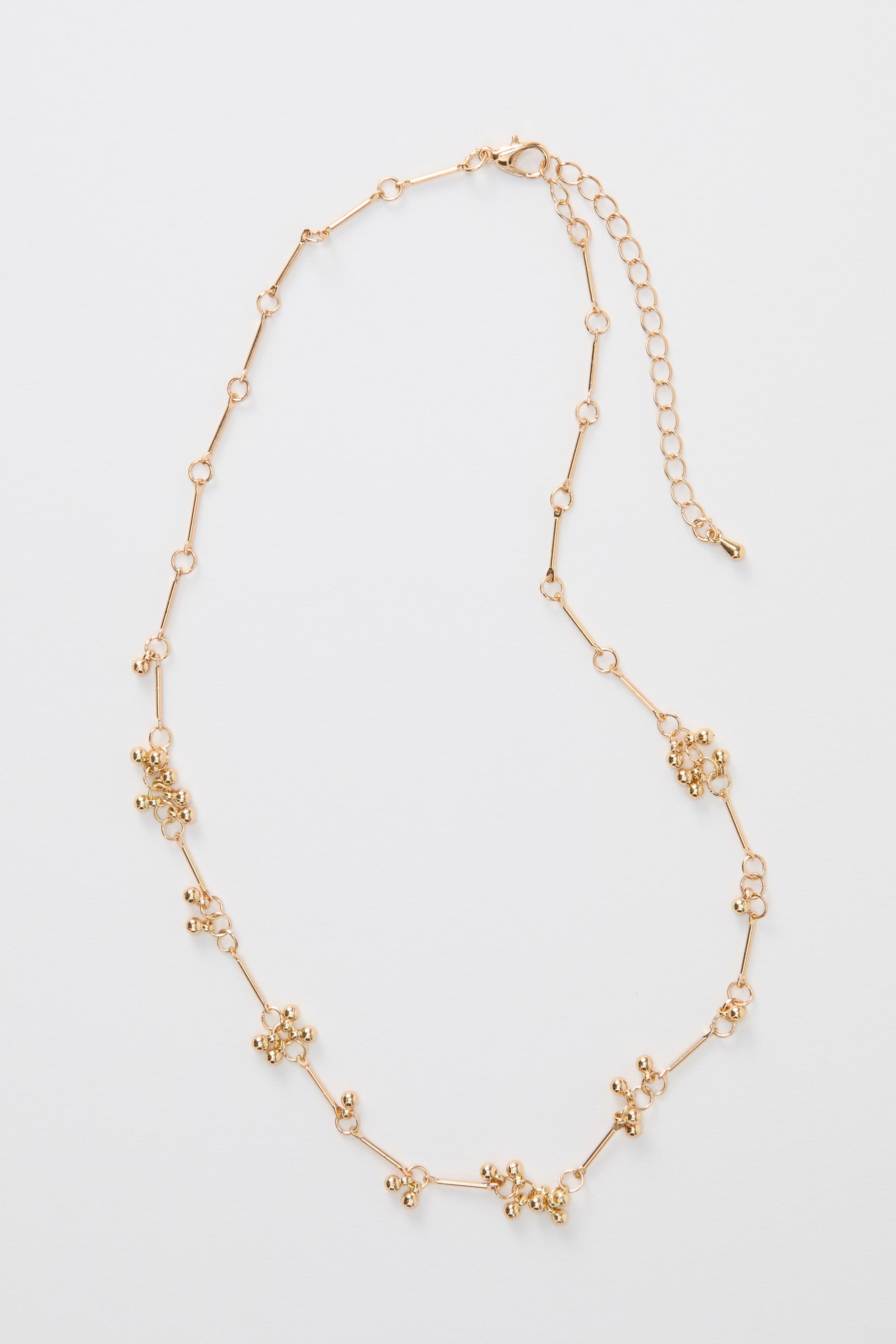 Ver imagen más grande: Un collar de tono dorado presenta una cadena de eslabones en barra, intercalada con racimos de pequeñas cuentas de metal, y muestra una cadena extensora ajustable con un cierre de gatillo.