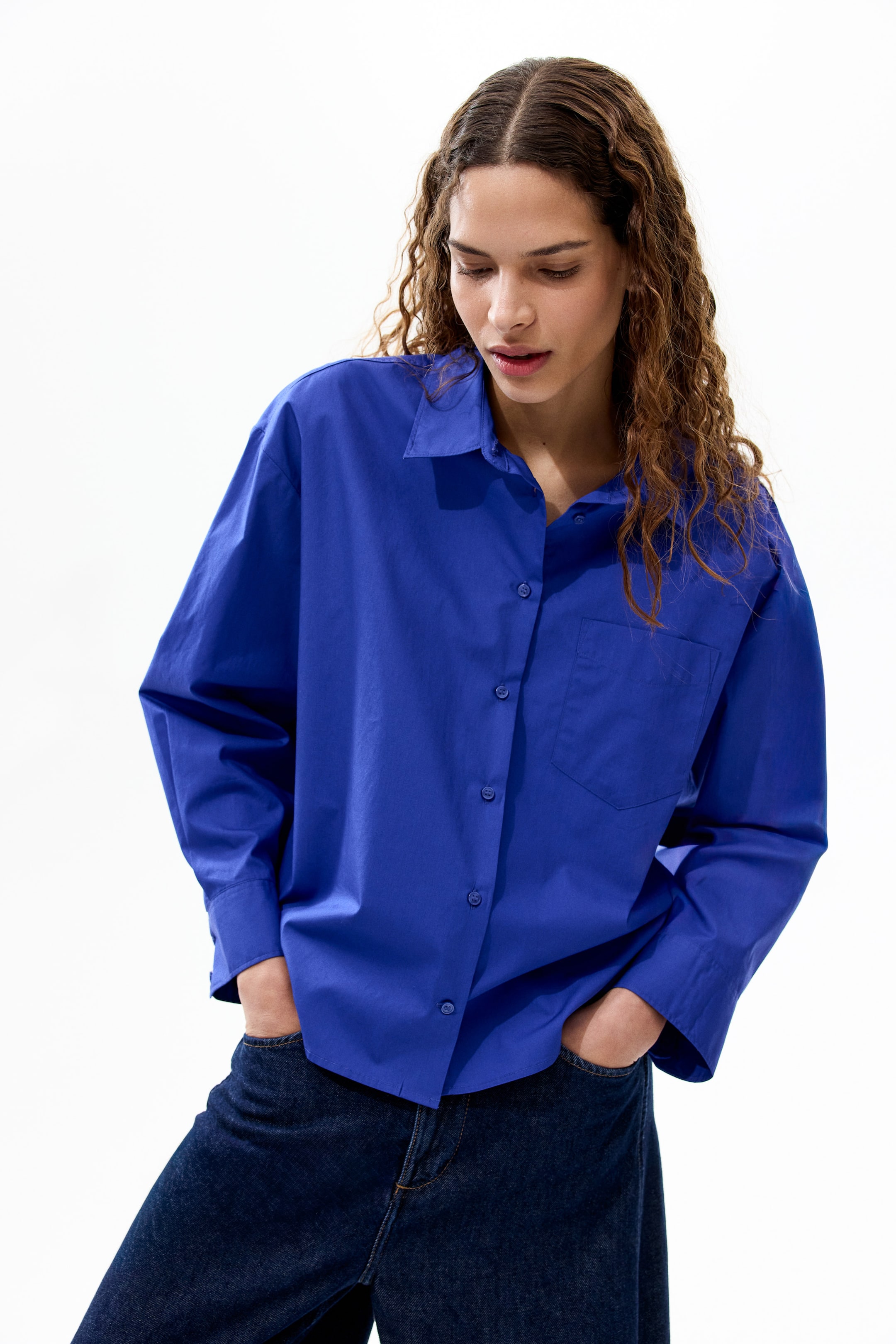 View larger image: Presenting a cobalt blue oversized button-up shirt, showcasing a pointed collar and a complete button placket. It highlights long sleeves with cuffs and a single chest pocket on the left side, worn in an untucked style.