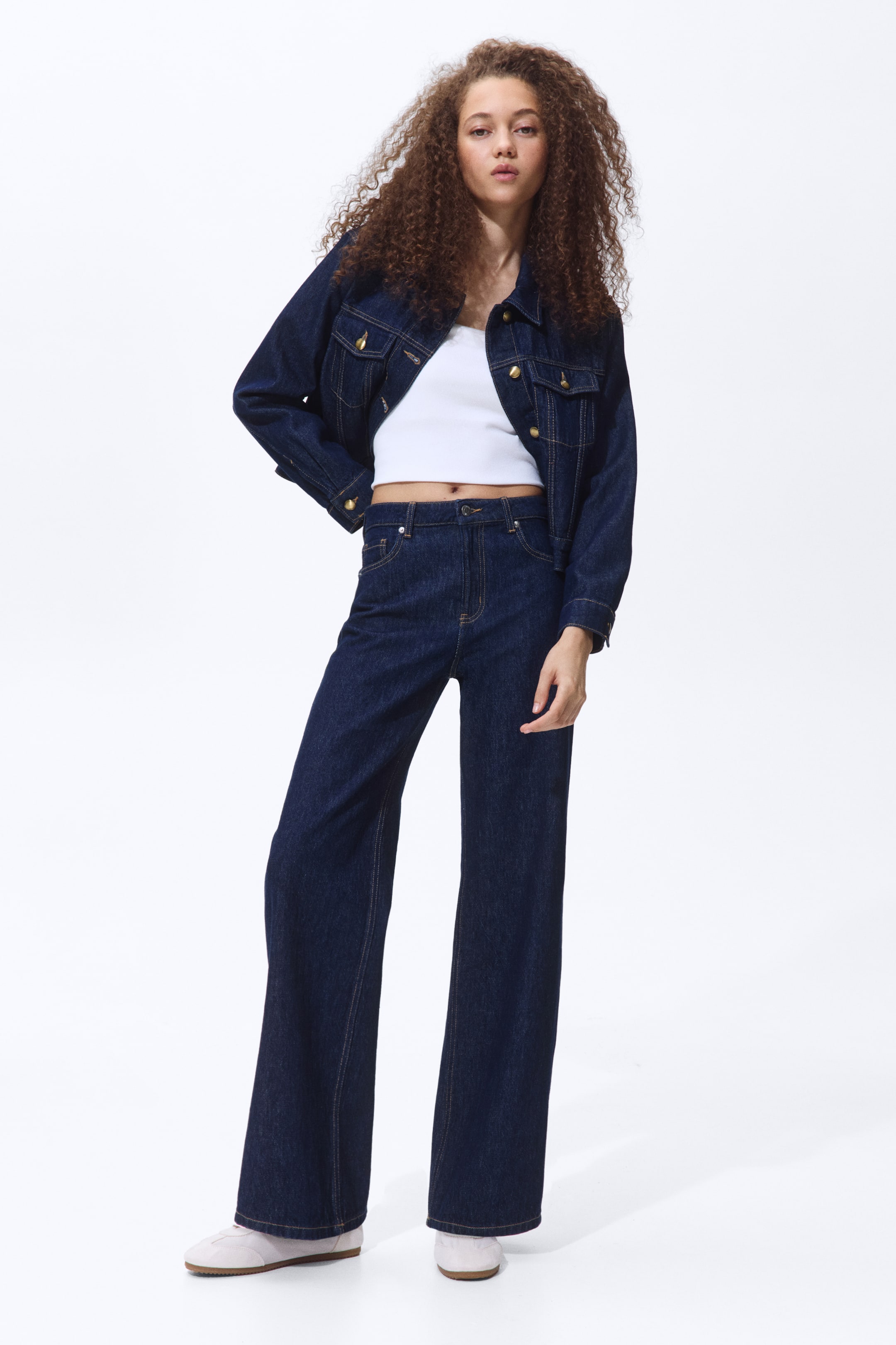 Größeres Bild anzeigen: 5-Pocket-Jeans aus gewaschenem Baumwoll-Denim mit hoher Taille, Reißverschluss und Knopf sowie weiten, geraden Beinen werden vom Model getragen, das steht und deren Passform präsentiert. Die Jeans sind mit einer dunklen Denimjacke gestylt.