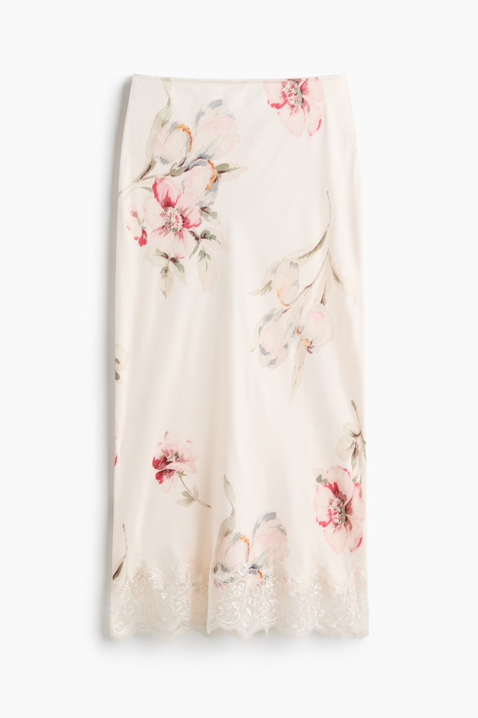 Une jupe de couleur crème arbore un motif floral aquarelle avec des fleurs roses et rouges ainsi qu'un feuillage vert. Elle présente une délicate bordure en dentelle festonnée le long de son ourlet inférieur. - 1