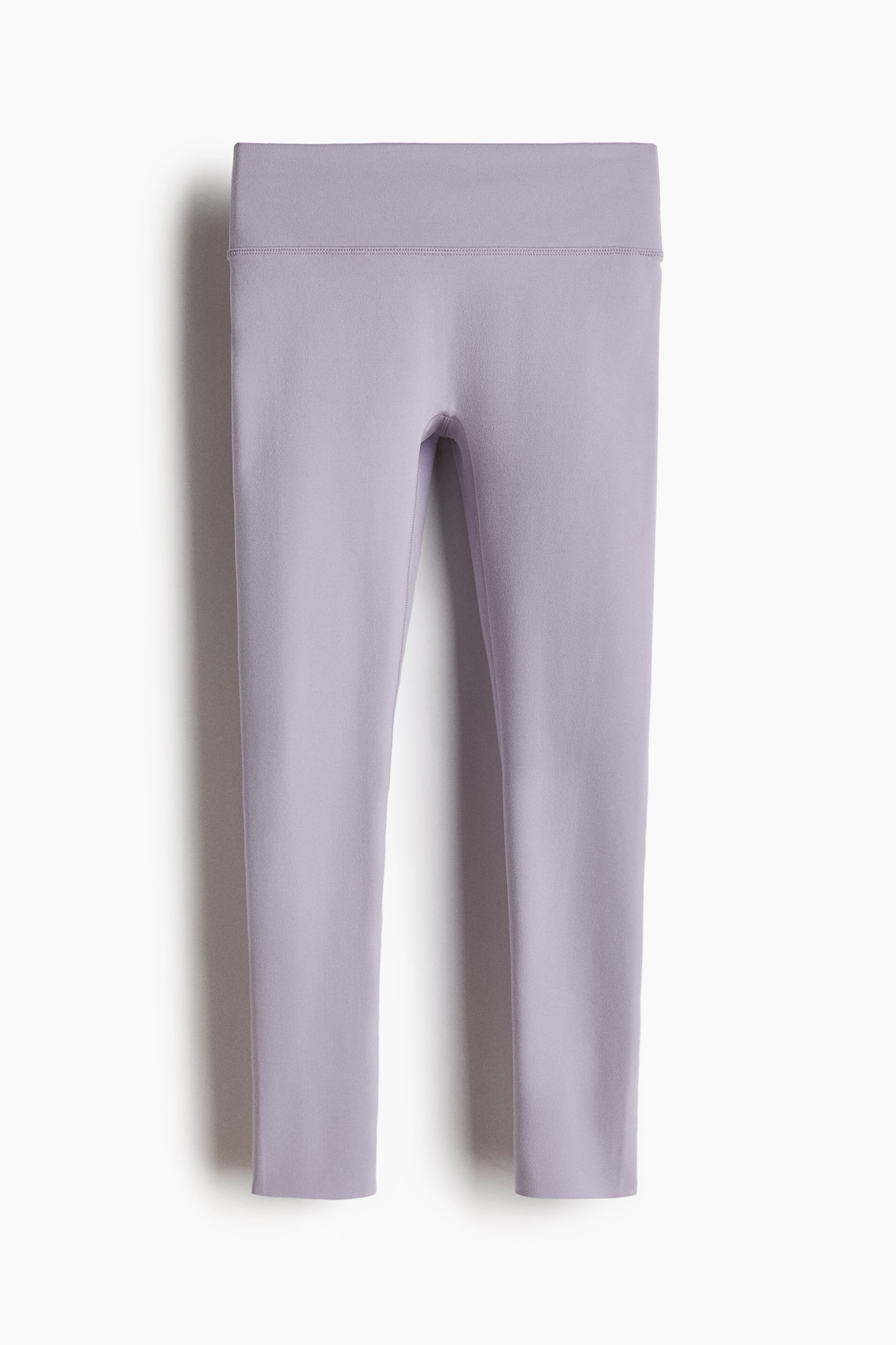 הצגת תמונה גדולה יותר: טייץ ספורט בצבע סגול בהיר מונחים שטוח, ומציגים את מראם הקדמי. הם מתאפיינים בגומי רחב וגבוה עם תפרים נראים לעין בקצוות העליון והתחתון, ובאורך קאפרי.