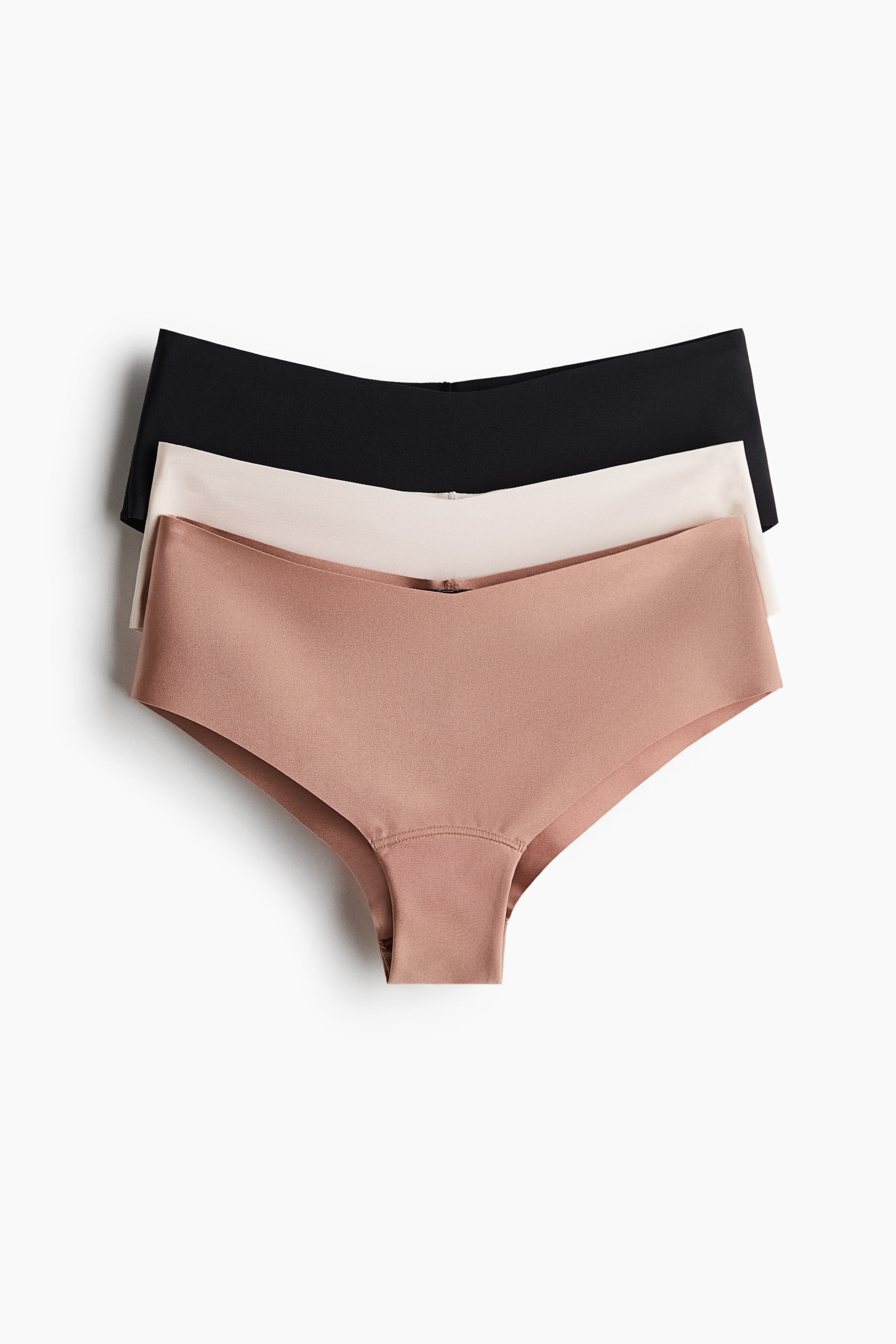 Agrandir l'image: Trois culottes sans coutures pour femmes sont empilées, présentées sous un angle légèrement surélevé à l'avant. La culotte du dessus est noire, celle du milieu est beige clair, et celle du bas est en taupe chaud, chacune arborant une construction lisse et plate avec une ceinture avant en forme de V.