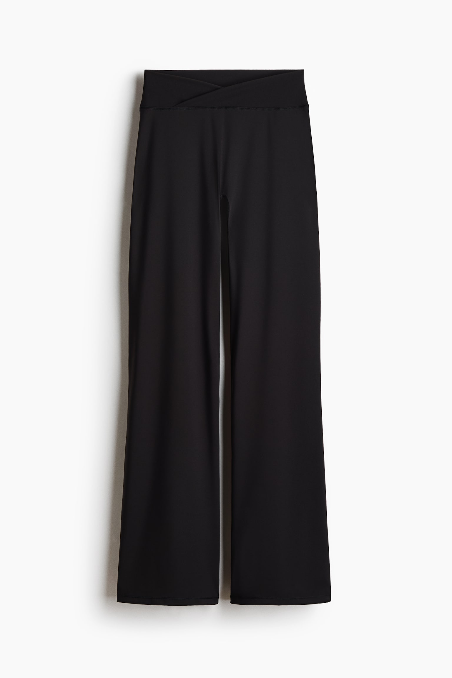 A pair of black wide-leg trousers is hanging front-on, showing a high-rise waistband with an overlapping crossover design. The trousers fall into a relaxed, wide-leg silhouette with a smooth finish.