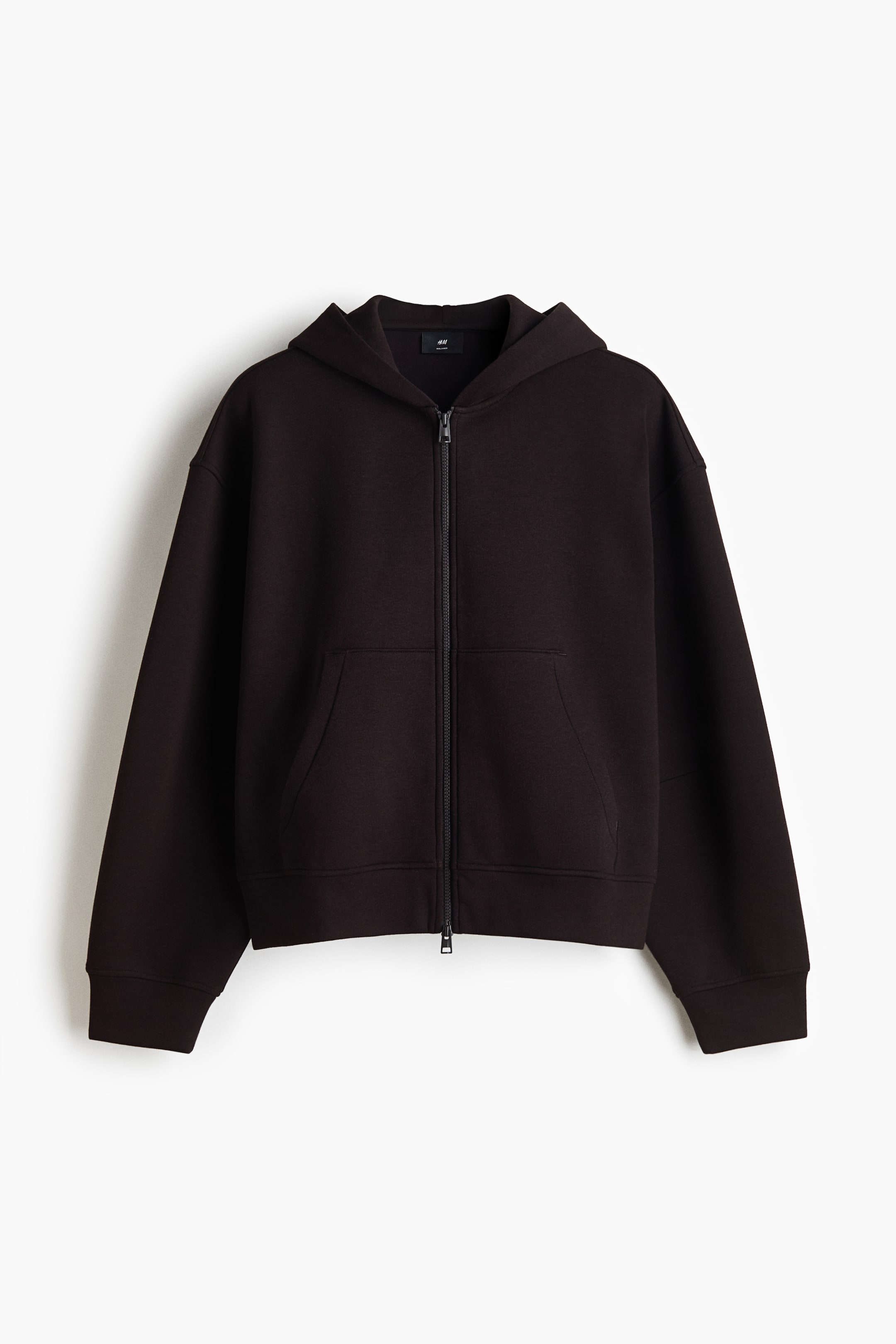 View larger image: A dark brown zip-up hoodie is shown from the front, featuring an attached hood, dropped shoulders, and a full-length double zipper. The garment showcases a split kangaroo pocket, along with ribbed detailing at the cuffs and hem.