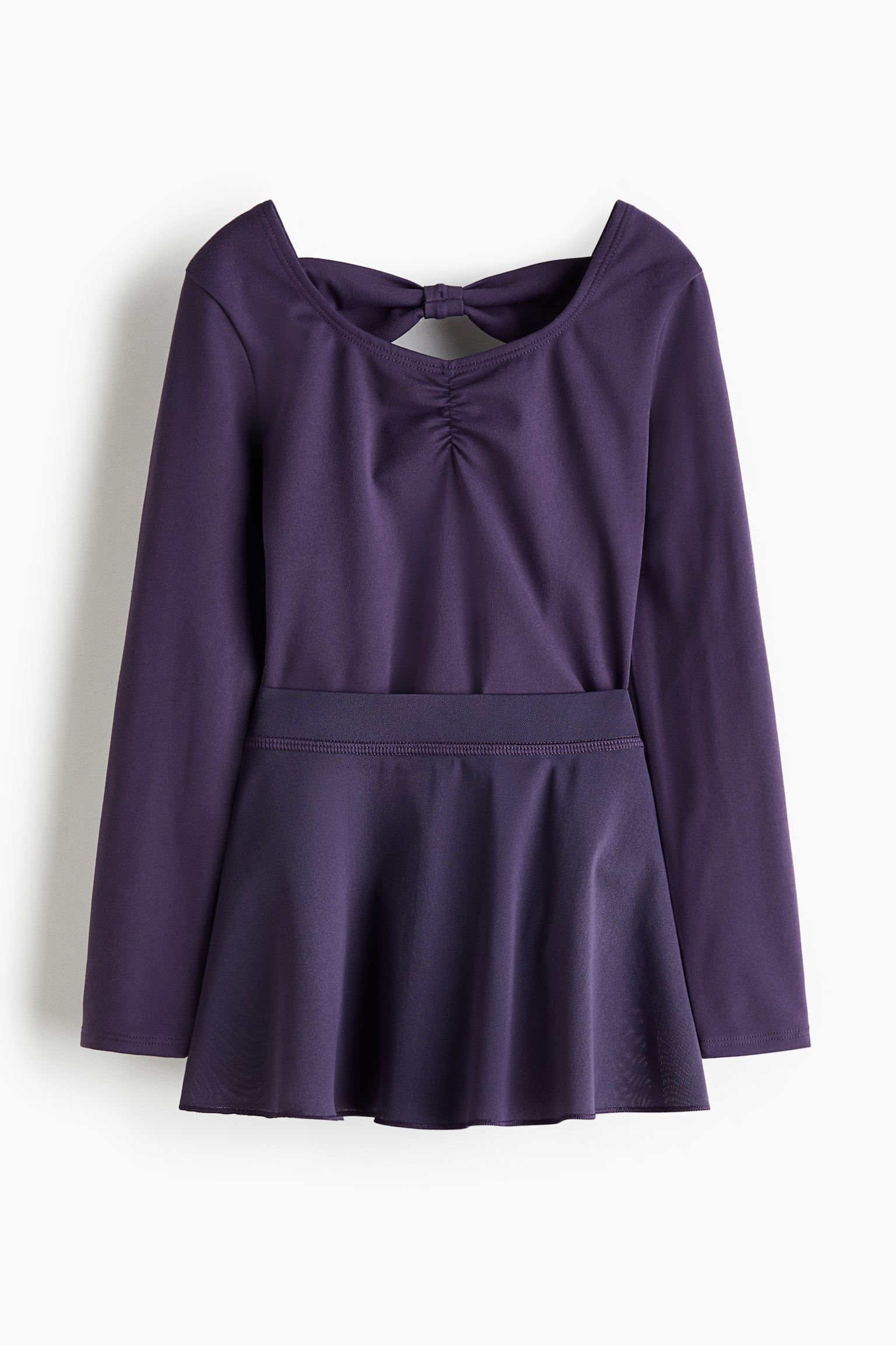 Un justaucorps à manches longues de couleur violet foncé avec une jupe attachée est posé à plat, mettant en valeur sa vue arrière. Le justaucorps présente un large dos ouvert avec un nœud attaché en haut et un froncement en dessous, tandis que la jupe attachée s'évase à partir d'une ceinture bien définie. - 1