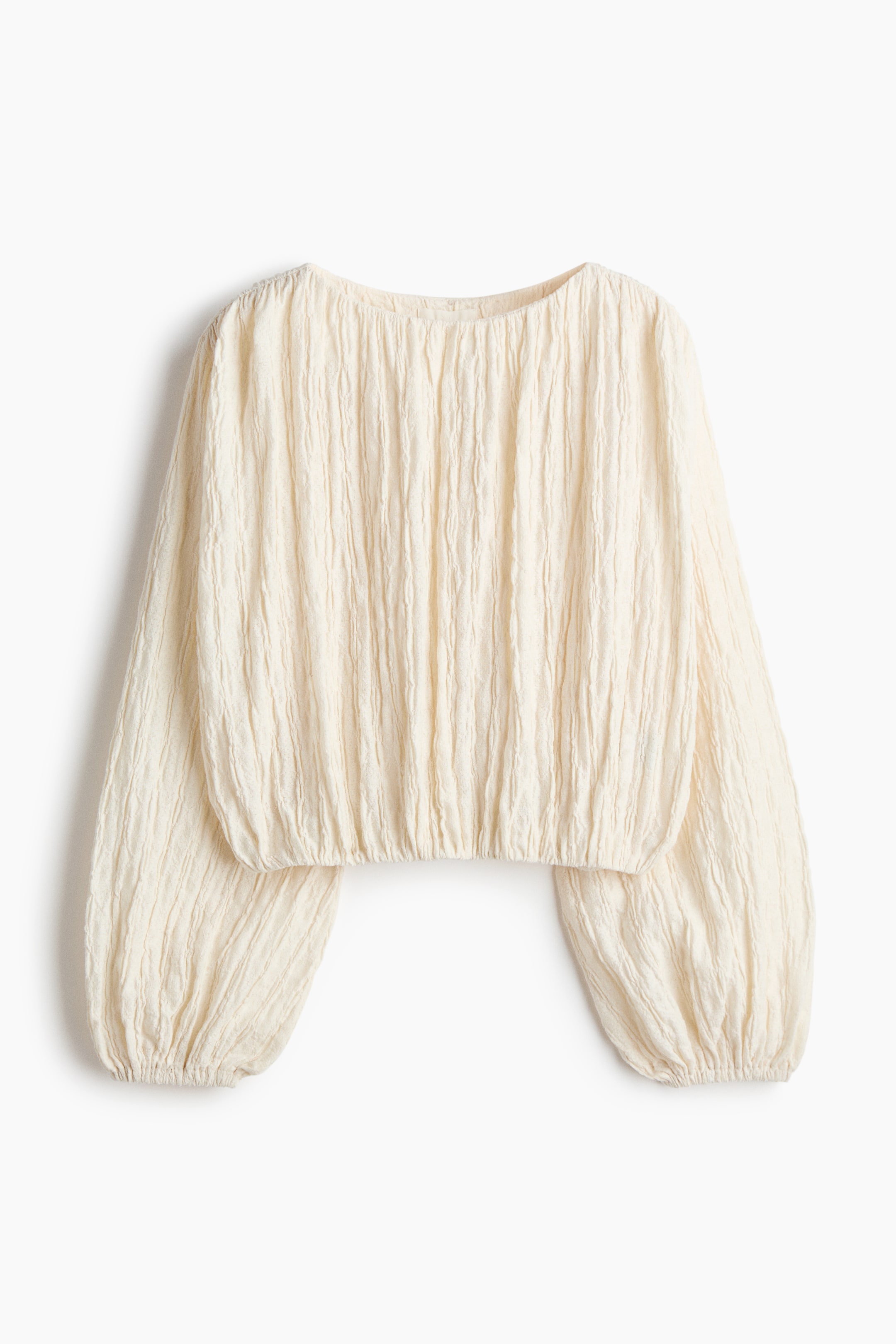 View larger image: A cream top showcasing a textured crinkled fabric is presented from the FRONT, highlighting a round neckline, long voluminous sleeves with elasticated cuffs, and an elasticated hem.