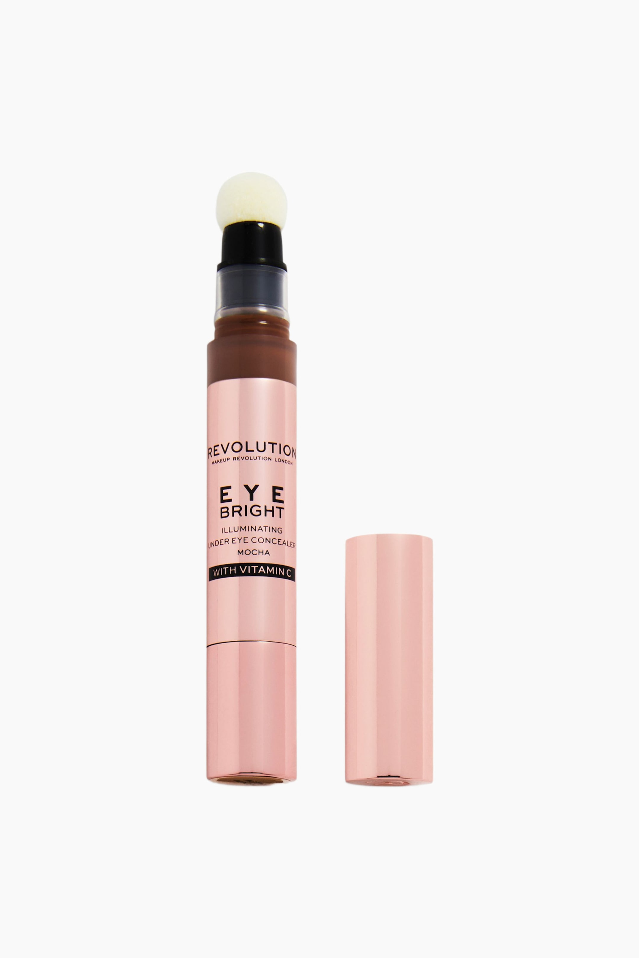 Visa större bild: Revolution Eye Bright Illuminating Under Eye Concealer i nyansen Mocha står upprätt och visar upp ett metalliskt rosa cylindriskt hylsa med en vit svampapplikator och en transparent hals som avslöjar den mörkbruna produkten inuti. Ett matchande metalliskt rosa lock står avtaget bredvid concealerpennan.