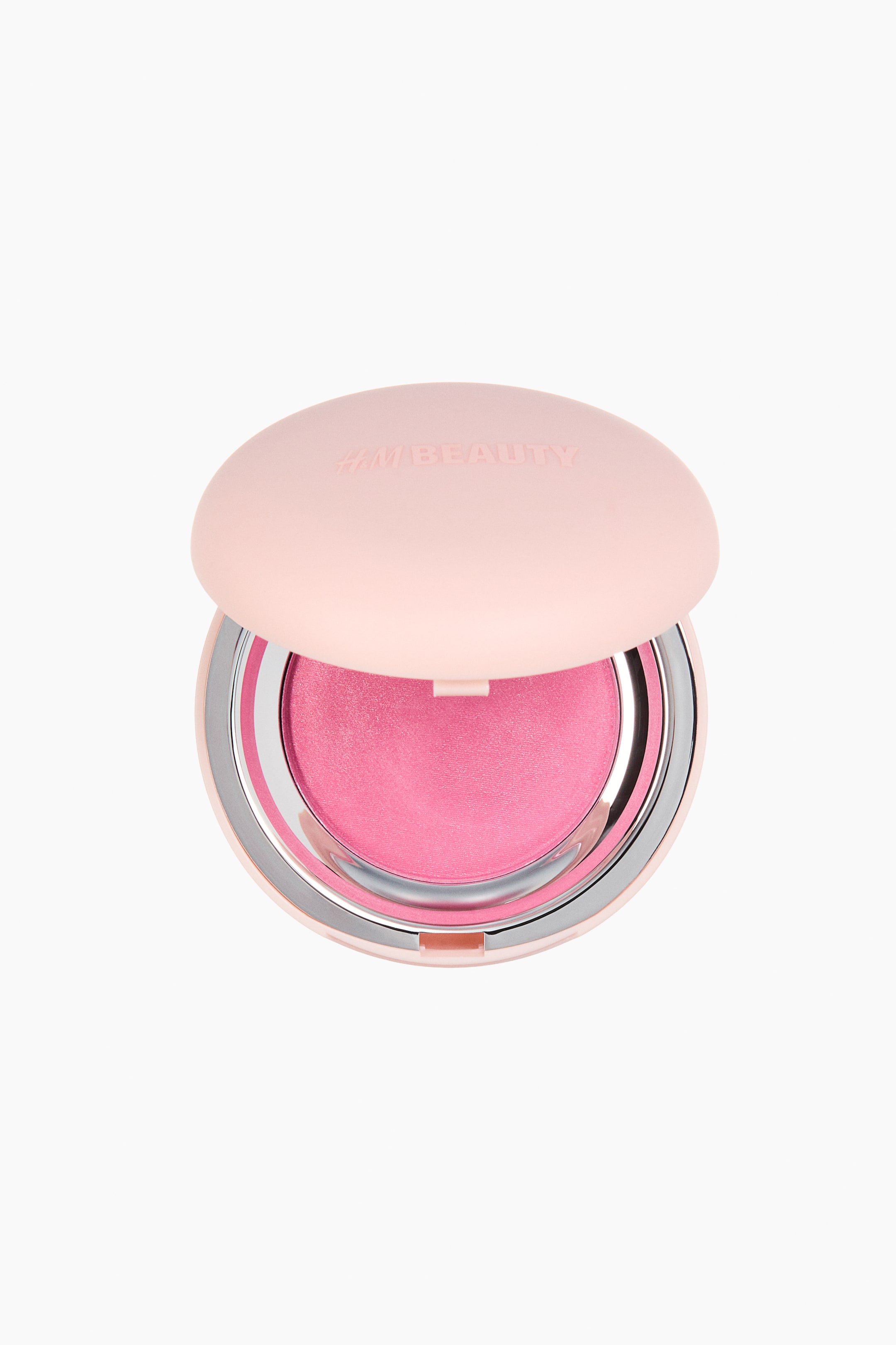View larger image: A cream-to-powder blush compact is facing front, showing its light-pink lid open with "H&M BEAUTY" embossed on top. The open compact reveals a circular pan of vibrant pink blush, encased in a shiny silver metallic rim.