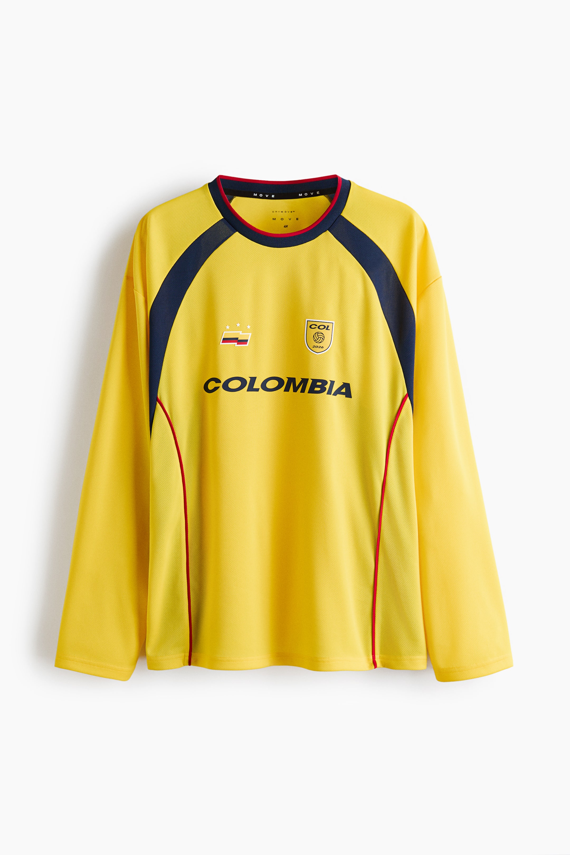 View larger image: A yellow long-sleeved jersey is displayed in the front, showcasing a dark blue trimmed round neckline with red piping. Dark blue panels extend from the neckline down the shoulders and sleeves, also outlined with red piping. The front of the jersey features the text 'COLOMBIA' in dark blue, accompanied by a rectangular striped emblem and three stars on the left chest. On the right chest, there's a circular emblem with 'COL', '2026', and a soccer ball graphic. Vertical red piping runs down the sides.