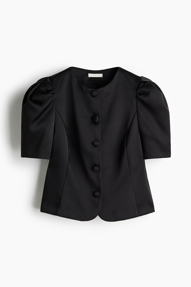 A black short blouse is presented FRONT, featuring a round neckline and a slight sheen. Its design includes covered buttons down the front, short sleeves with pleats at the top, and princess seams. - 1