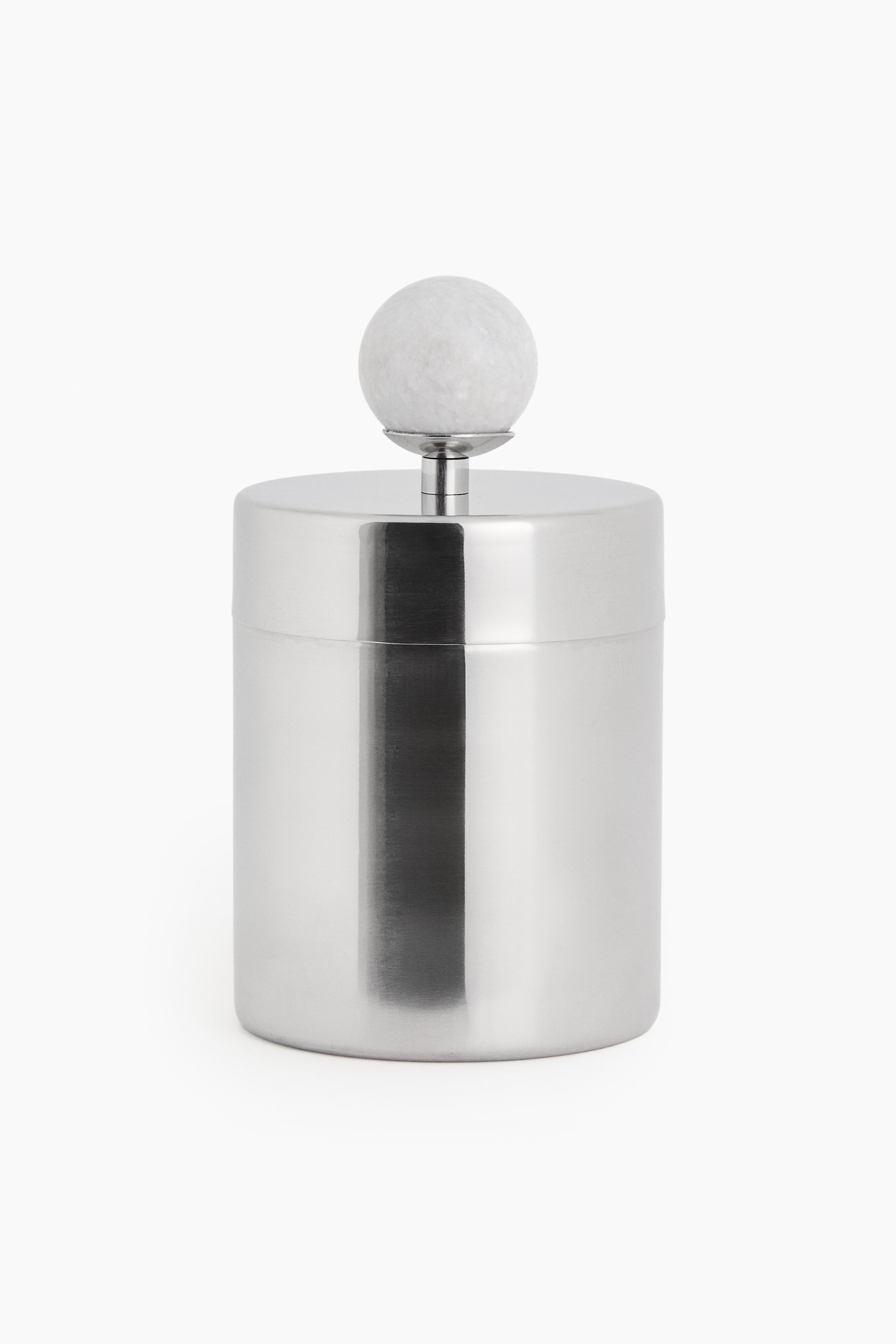 View larger image: A cylindrical polished stainless steel container is standing front-facing, featuring a flat lid. A white spherical marble knob is topping the lid, attached by a small metal stem.