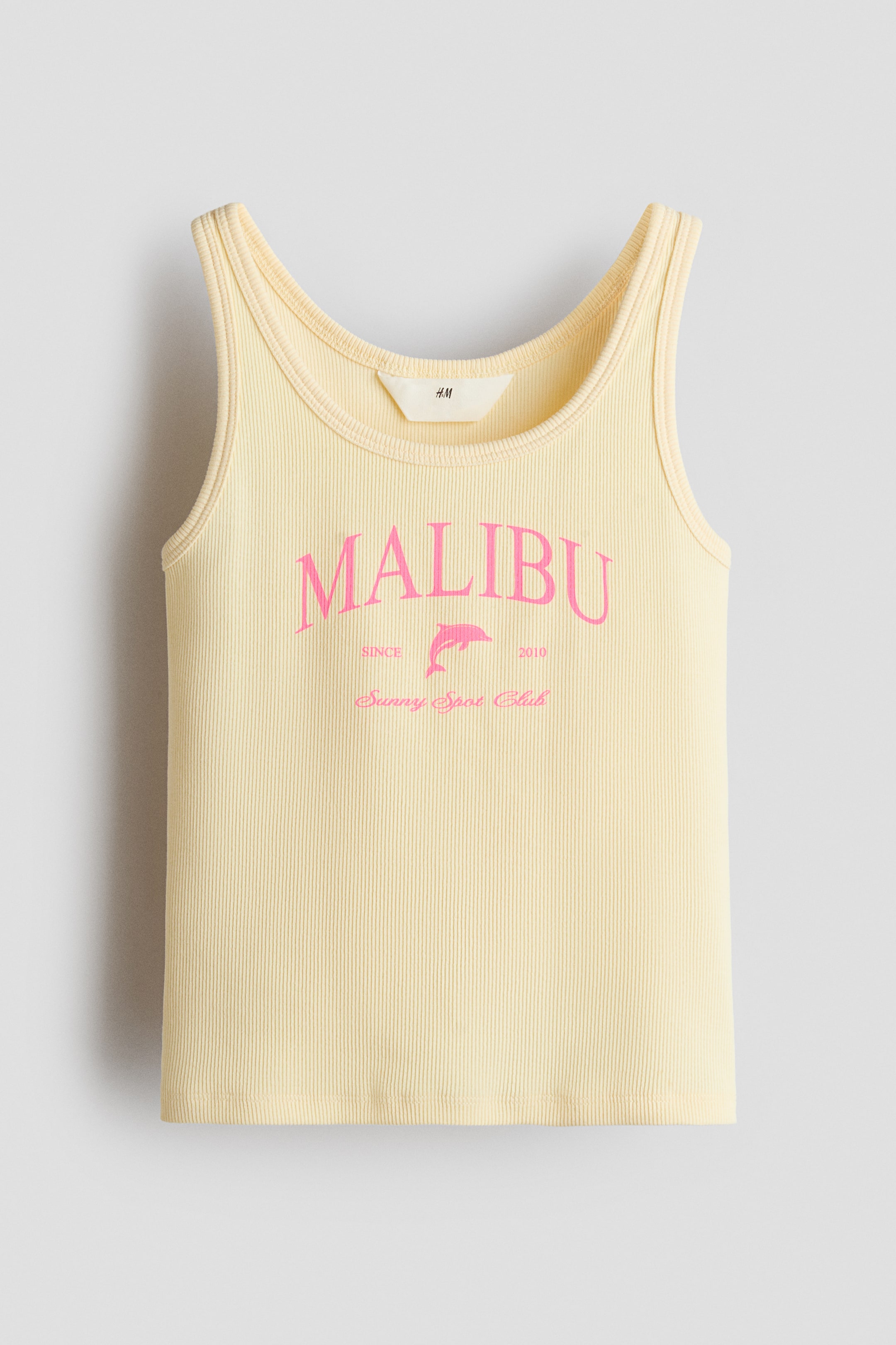 View larger image: A light yellow, ribbed cotton jersey vest top is displayed from the front, showcasing a pink 'MALIBU' print with a dolphin graphic and 'Sunny Sport Club' text on the chest. Narrow trims complete the neckline and armholes.