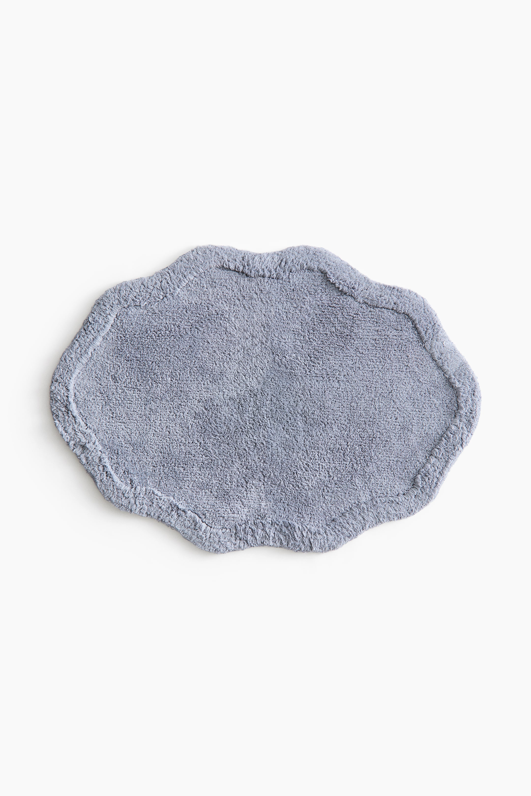 View larger image: Presenting a light blue-grey bath mat that highlights its tufted cotton texture and an art deco-inspired wavy silhouette. It boasts a distinct raised border along its edges.