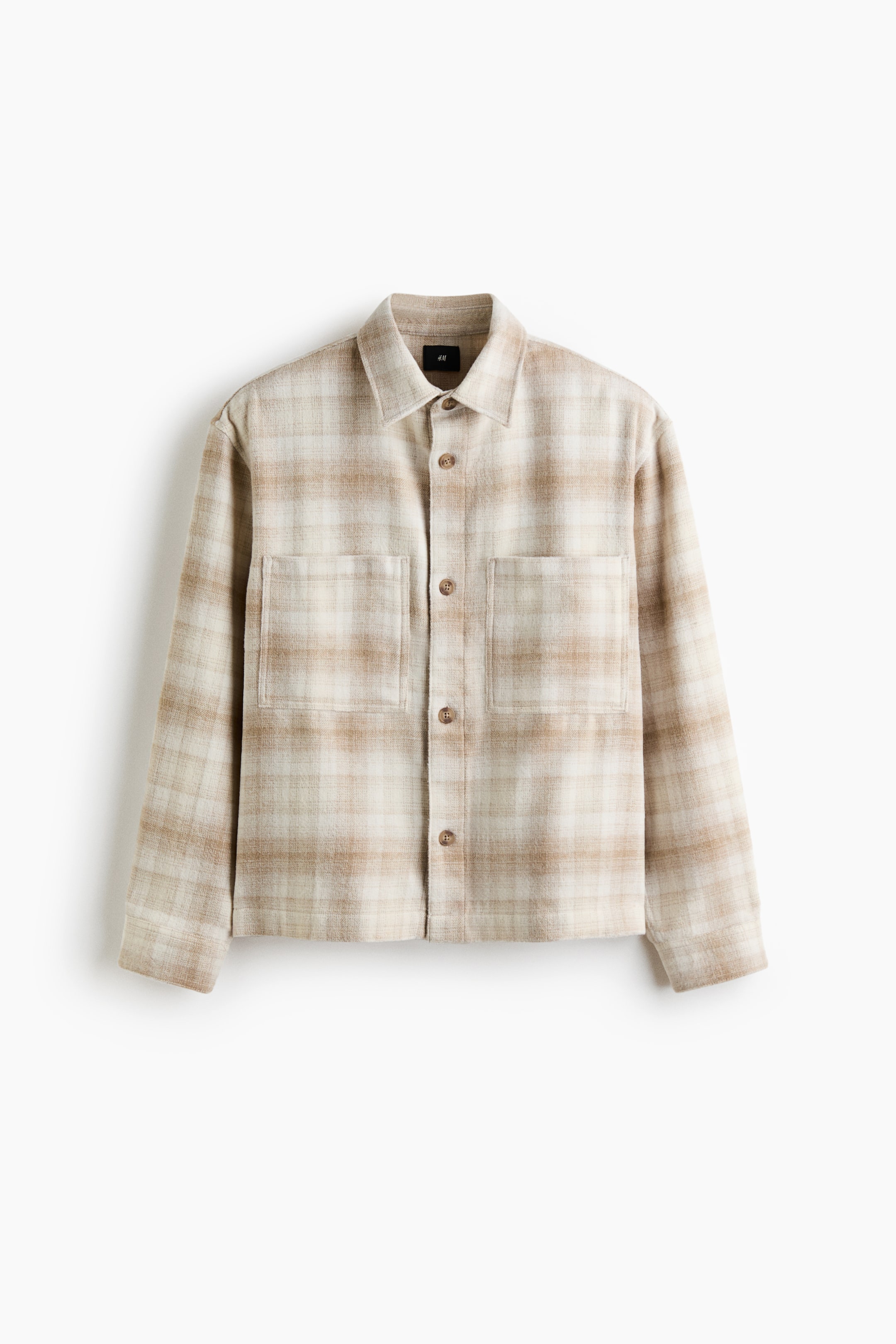Voir une image plus grande: Une chemise à carreaux orientée vers l'avant présente un motif beige et crème. Elle est conçue avec un col pointu, une fermeture à boutons à l'avant avec des boutons bruns, deux poches poitrine à rabat boutonnées et des manches longues avec des poignets boutonnés.