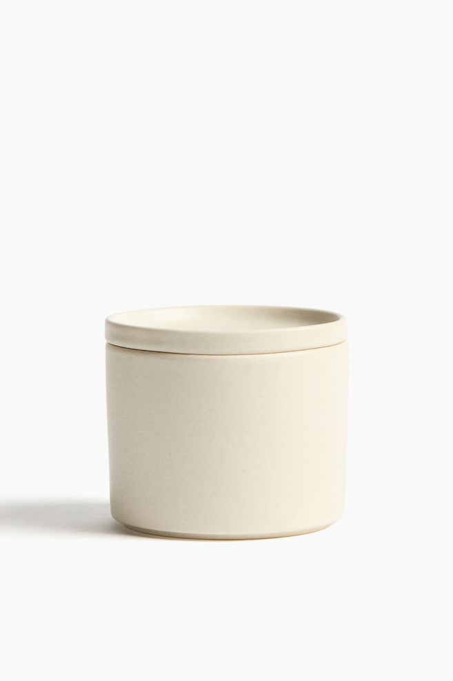 An off-white, matte cylindrical container with a flat, snug-fitting lid is facing FRONT. - 1
