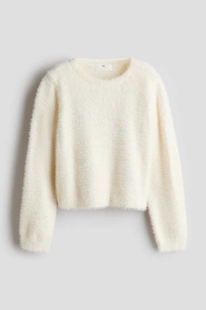 Un suÃ©ter tejido esponjoso color crema, visto de frente, con cuello redondo, mangas largas y un acabado suave con textura de pestaÃ±as. El suÃ©ter presenta un dobladillo recto ligeramente corto. - 1