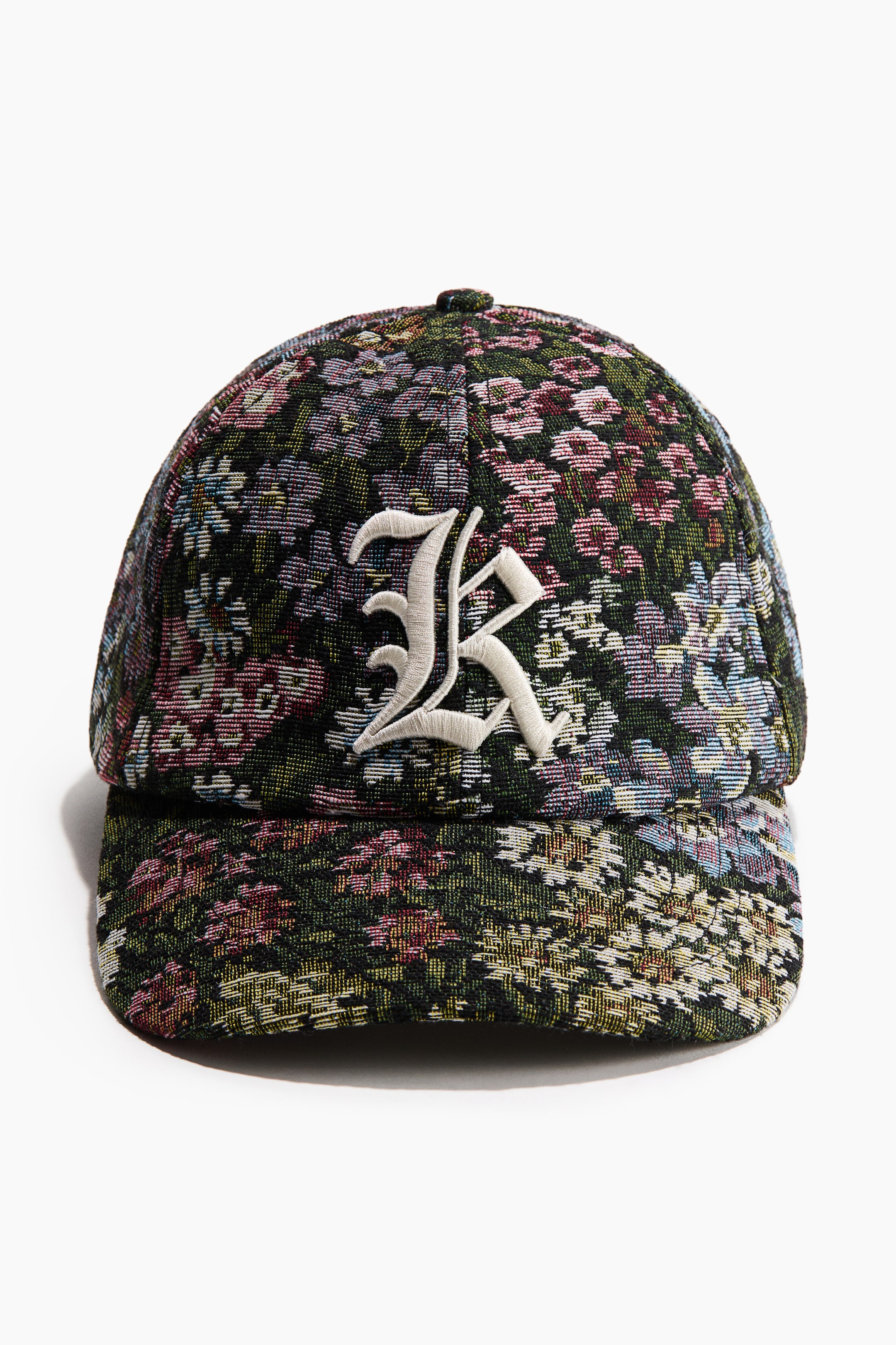 View larger image: A forward-facing cap showcases a lively, multi-hued floral tapestry design across its crown and brim. A distinct, light-toned embroidered "R" is prominently centered on the front of the cap.