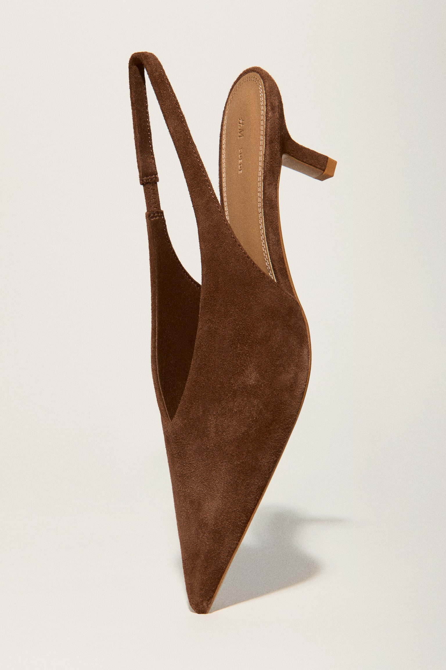 A brown suede slingback shoe is displayed from a side angle, showcasing a pointed toe and a kitten heel. - 1