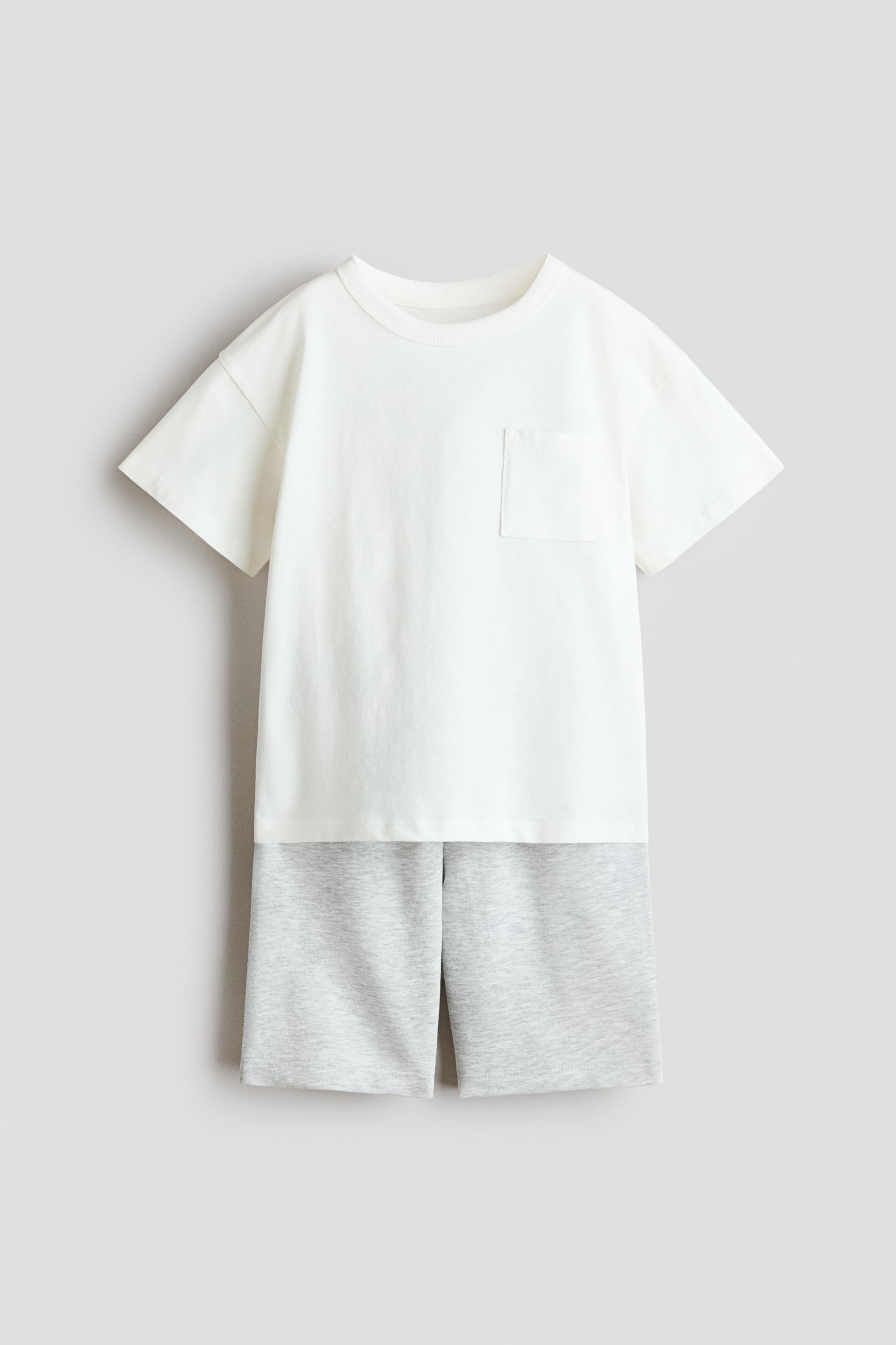 View larger image: This two-piece set showcases a white short-sleeved t-shirt with a ribbed crew neck and a chest patch pocket, paired with light grey heather shorts.