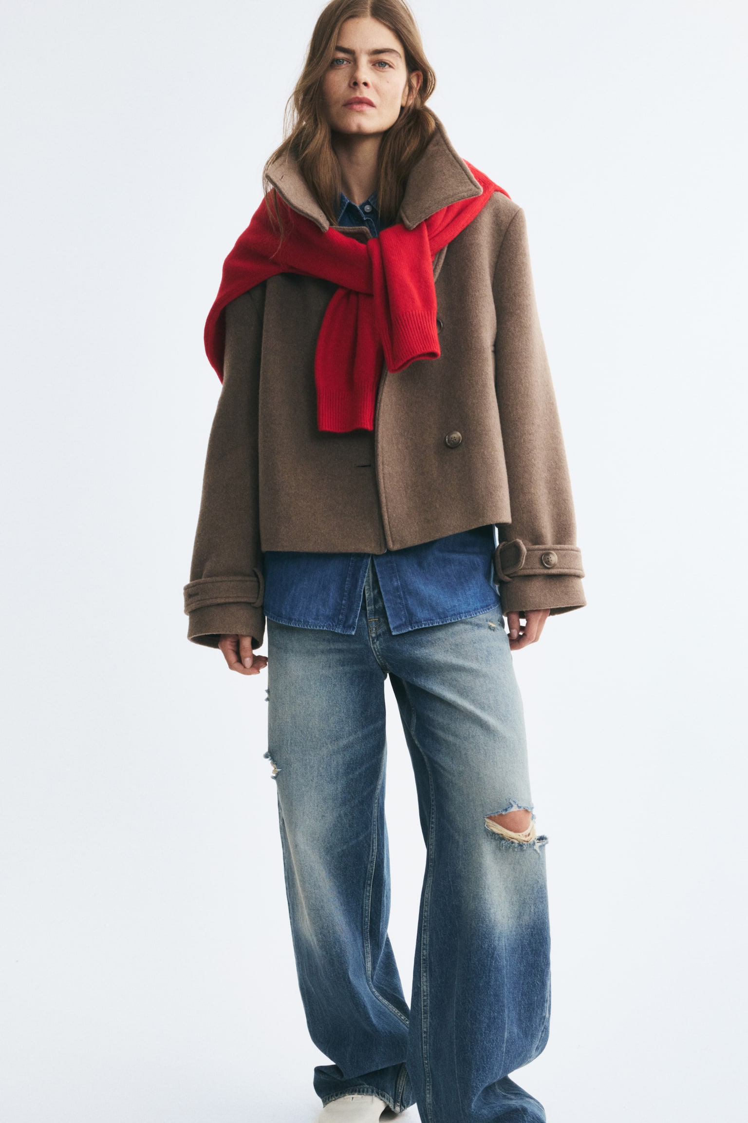 An oversized brown wool-blend jacket is shown from a front angle, featuring a high, buttoned funnel collar and an asymmetrical button-down front closure. The jacket presents a soft, felted texture with vertical welt pockets and long sleeves finished with button-tab cuffs. - 1