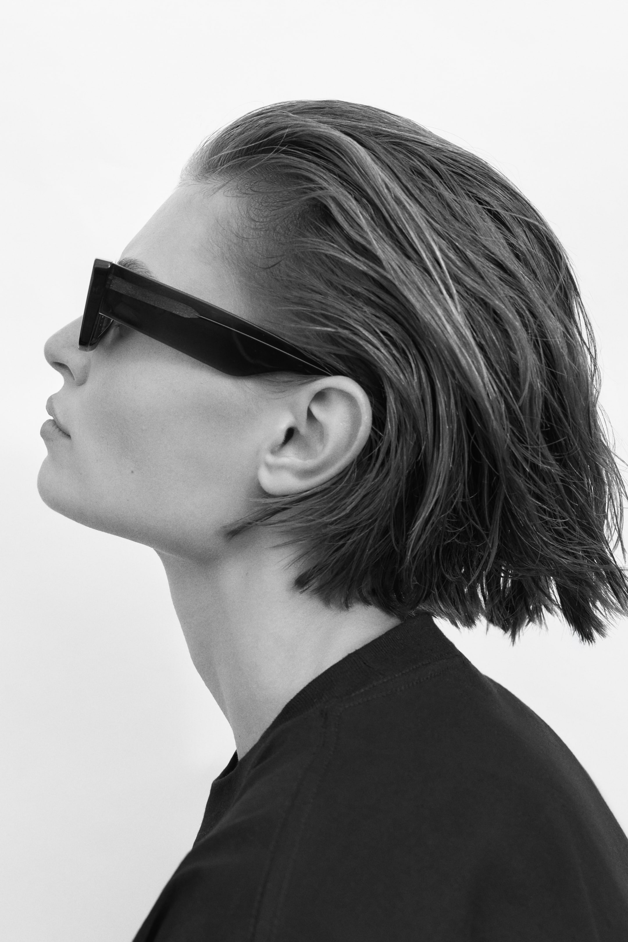 View larger image: Black sunglasses display thick, rectangular frames and dark lenses. Their wide temple arms extend straight back as they rest on a face, with the product shown in left profile.