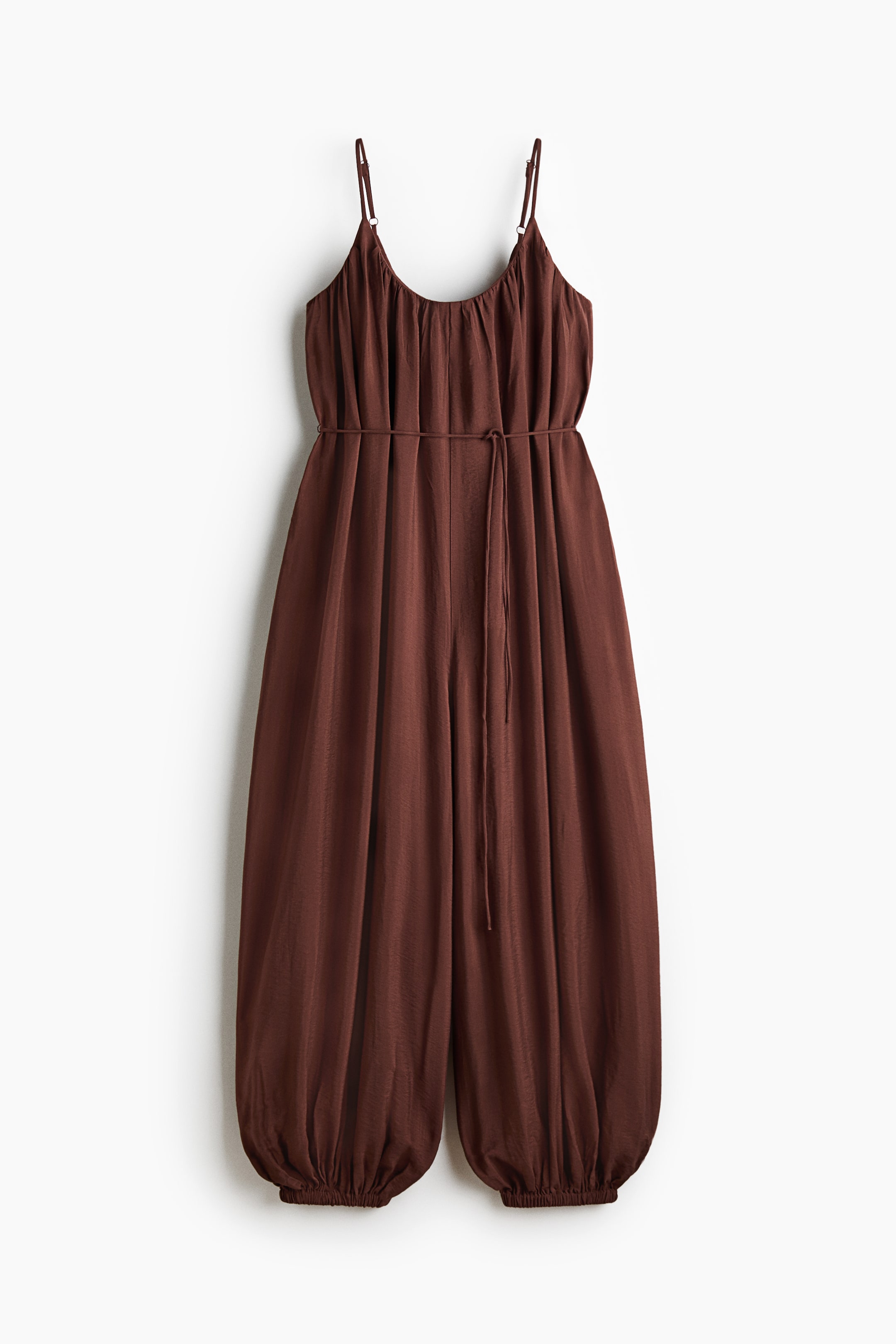 View larger image: Presenting a relaxed-fit brown jumpsuit, showcasing its front with a gathered scoop neckline and slender, adjustable spaghetti straps. The waist is cinched with spaghetti ties, while the ankle-length balloon legs conclude with elasticated hems.