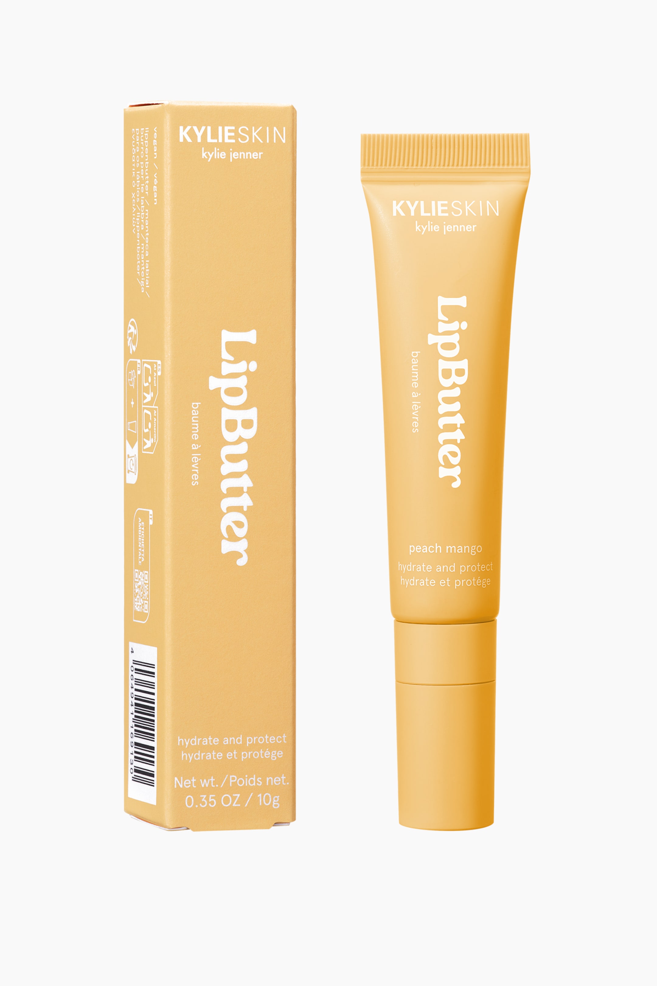 Vis større bilde: Et lys ferskenfarget LipButter-rør og dens rektangulære emballasjeboks står oppreist, plassert side om side og vendt litt fremover. Røret viser en ribbet, forseglet topp sammen med 'KYLIESKIN kylie jenner', 'LipButter', 'peach mango', og 'hydrate and protect' tekst, og er toppet med en matchende base. Boksen viser lignende branding og produktdetaljer på sin front og synlige side.
