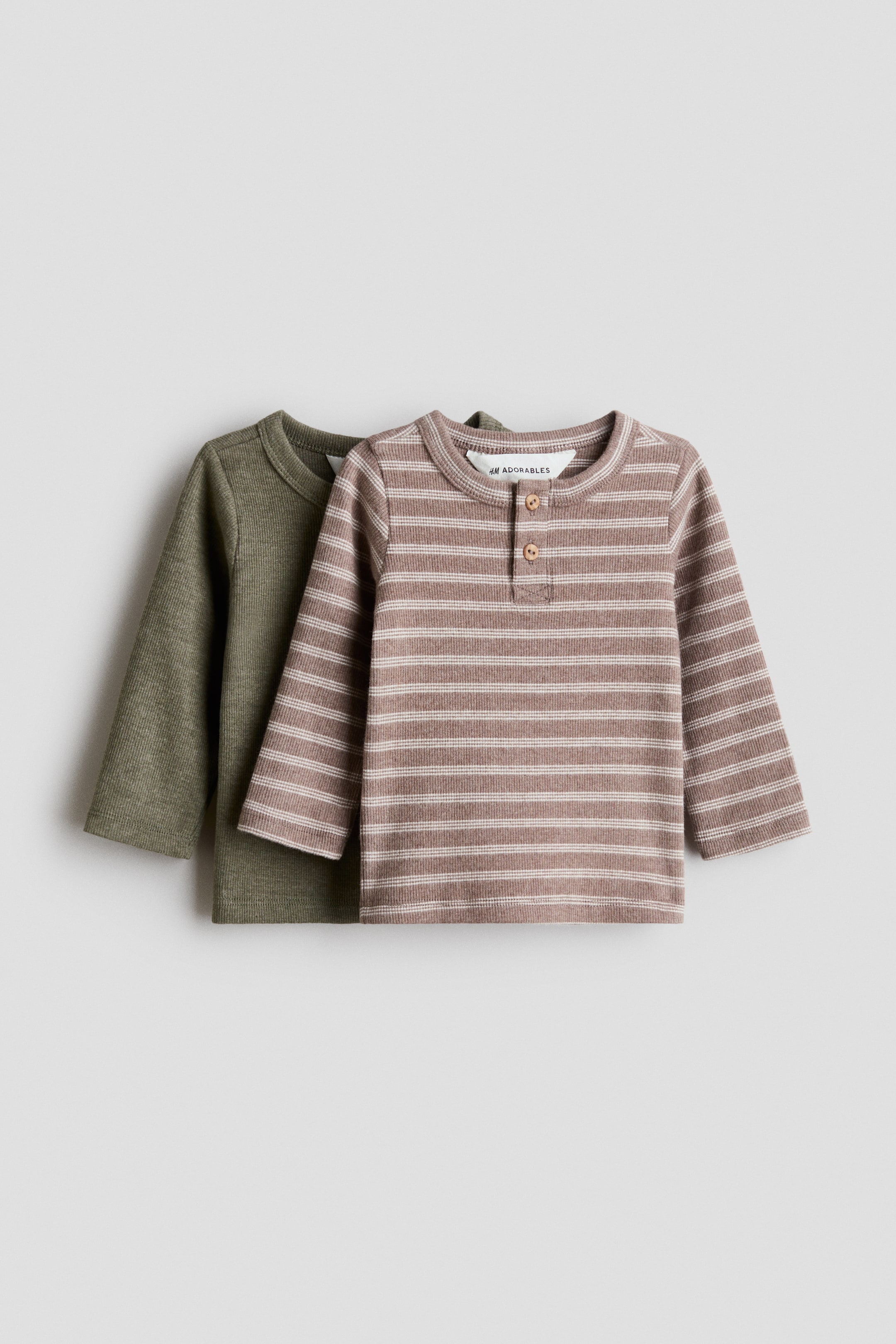 View larger image: Two long-sleeve ribbed knit shirts are lying flat, with an olive green shirt partially behind a brown and light beige striped Henley shirt. The striped shirt features a three-button placket with wooden buttons.