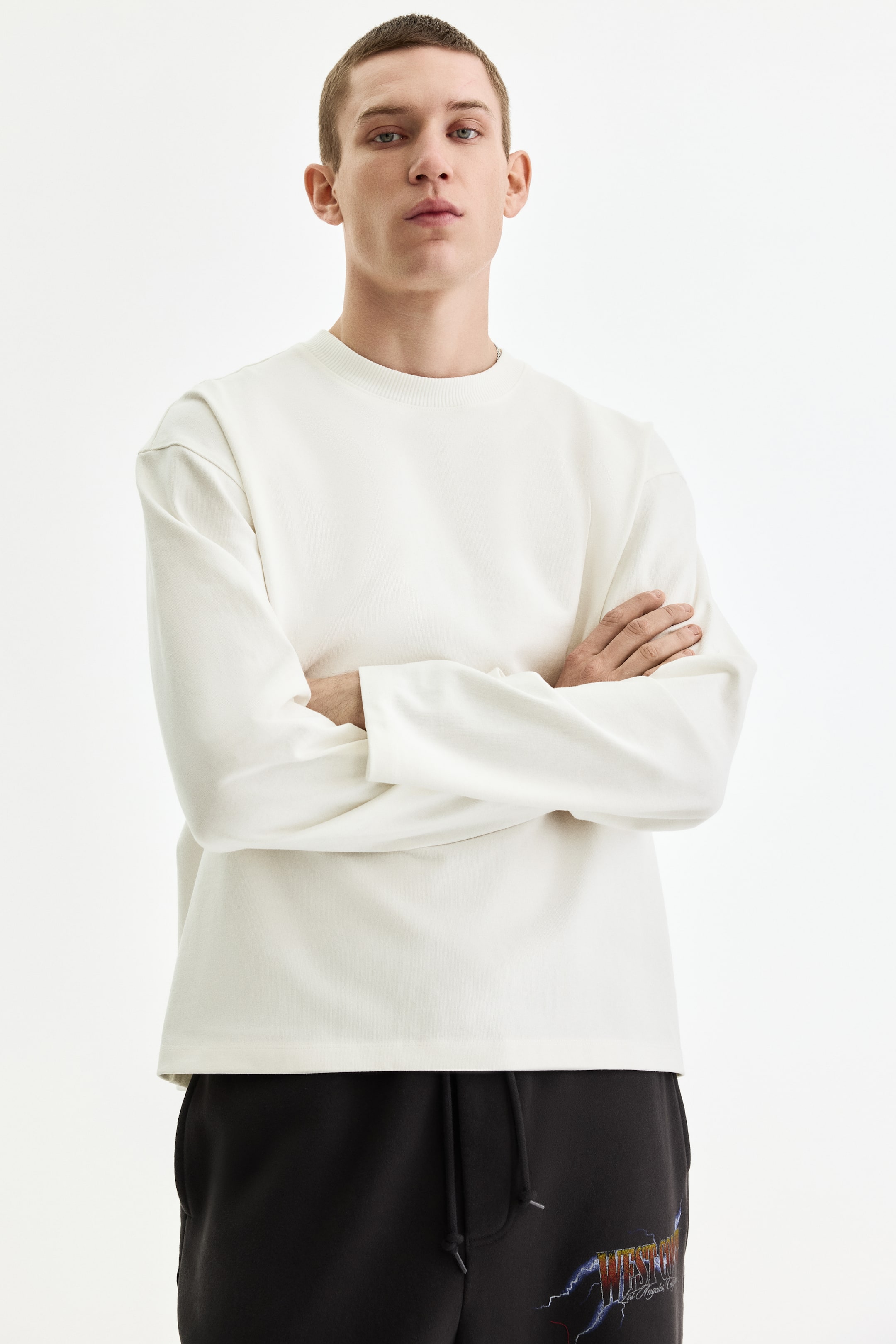 View larger image: The off-white long-sleeved crewneck top is shown facing forward, featuring a relaxed fit, plain cuffs, and a straight hem.