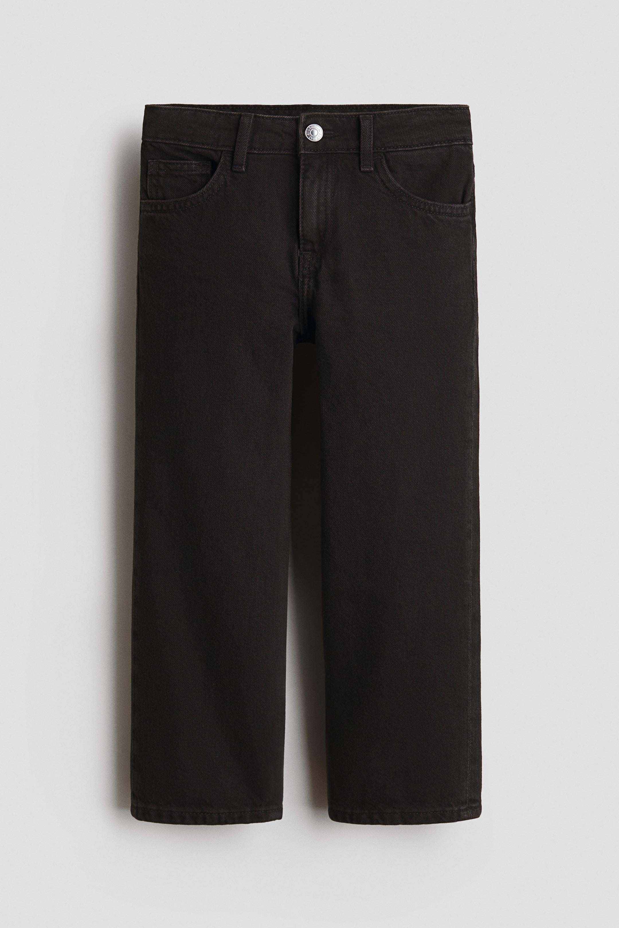 View larger image: The black denim 5-pocket jeans are shown from the front, featuring a silver-toned button closure, a zip fly, and front and coin pockets. They exhibit a loose fit through the hip, thigh, and leg.