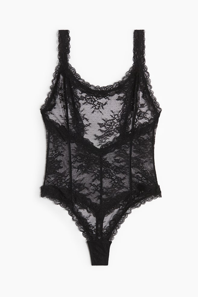 A black lace bodysuit is displaying from the front, featuring a sheer floral lace pattern with scalloped trim along the neckline, armholes, and thong-style leg openings, and visible structural seams running down the torso. - 1