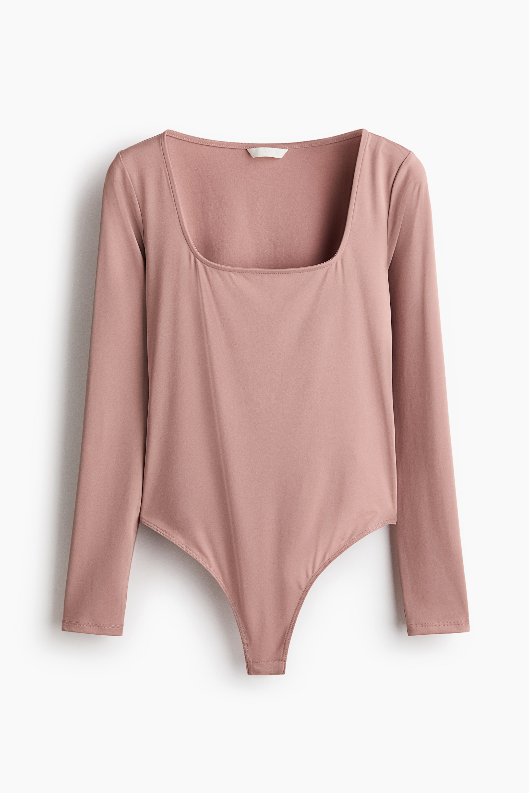 Agrandir l'image: Un body-string rose poudré est posé à plat, vu de face, présentant une encolure carrée, des manches longues et un tissu jersey lisse et extensible.