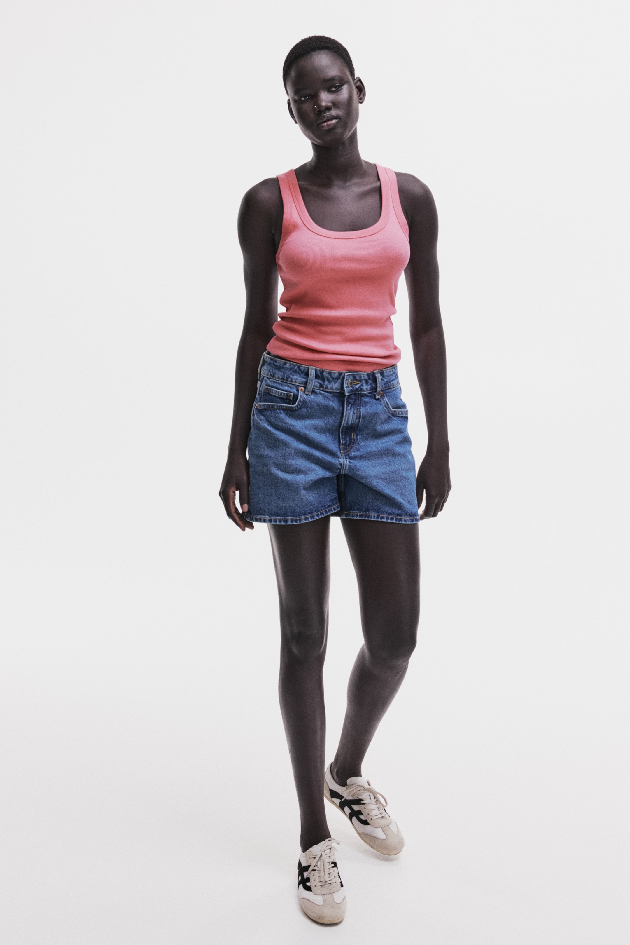 View larger image: Denim shorts feature a mid-blue wash and a relaxed fit, shown from the front. They are designed with a classic five-pocket style, a standard waistband with belt loops, ending at mid-thigh.