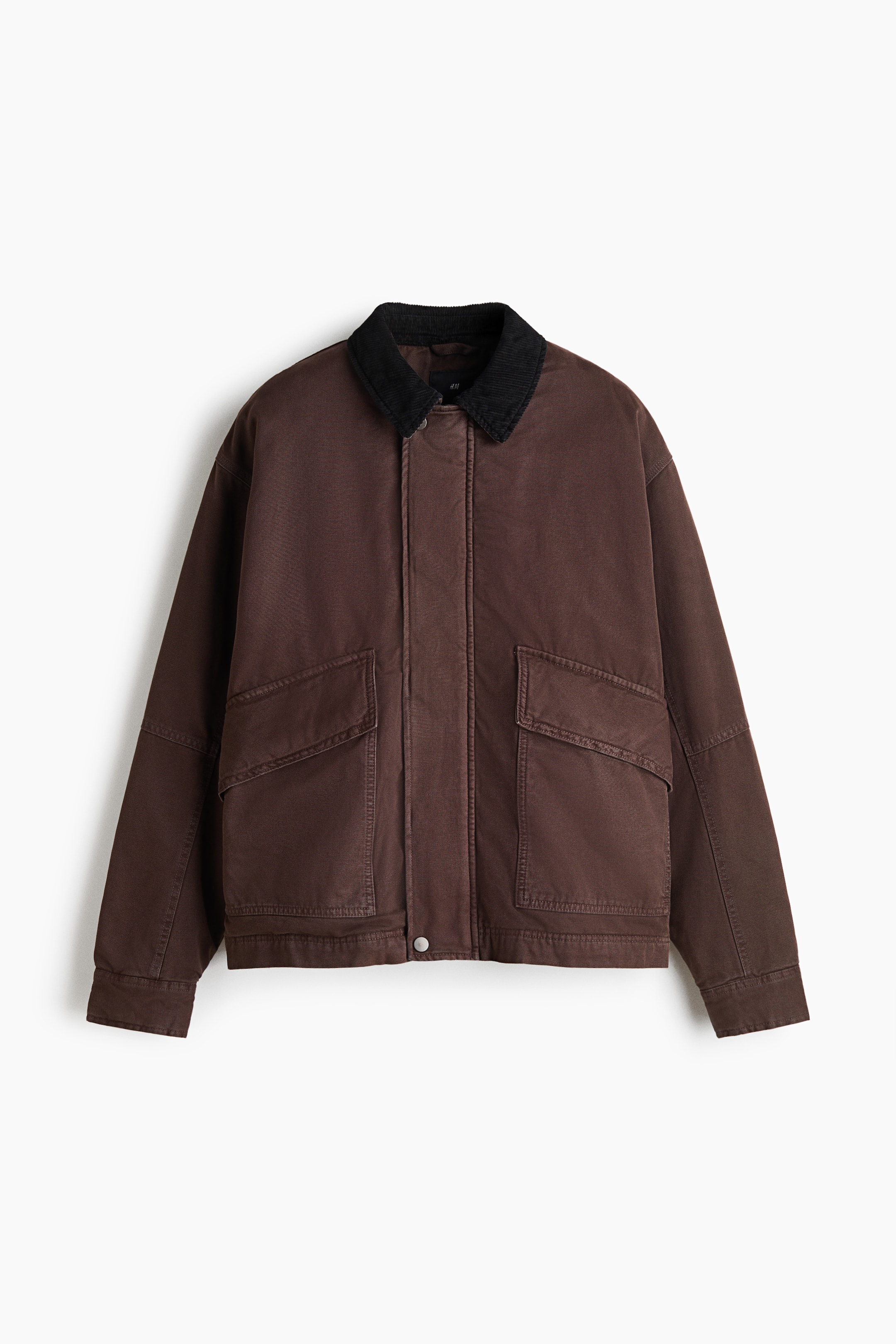 View larger image: A brown utility jacket is shown from the front, featuring a contrasting black corduroy collar and a concealed front closure with a single snap button at the hem. It has a relaxed, boxy fit with dropped shoulders, long sleeves, and two large front pockets with angled flaps.