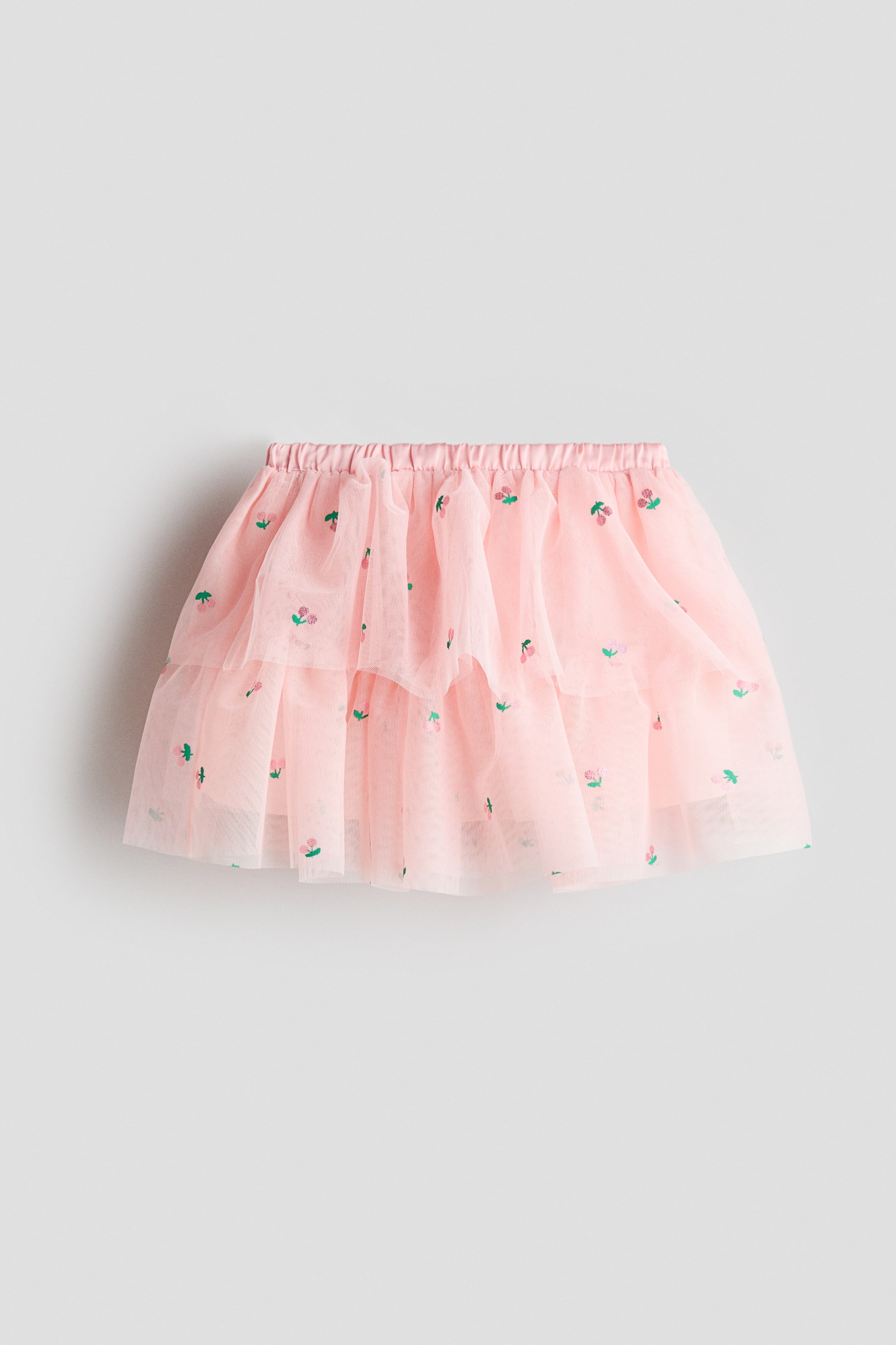 View larger image: A pink tulle skirt is showcased from the front. It boasts an elasticated, gathered waistband and multiple layers of pink tulle. Delicate, embroidered cherry motifs in pink and green are sprinkled across the skirt.