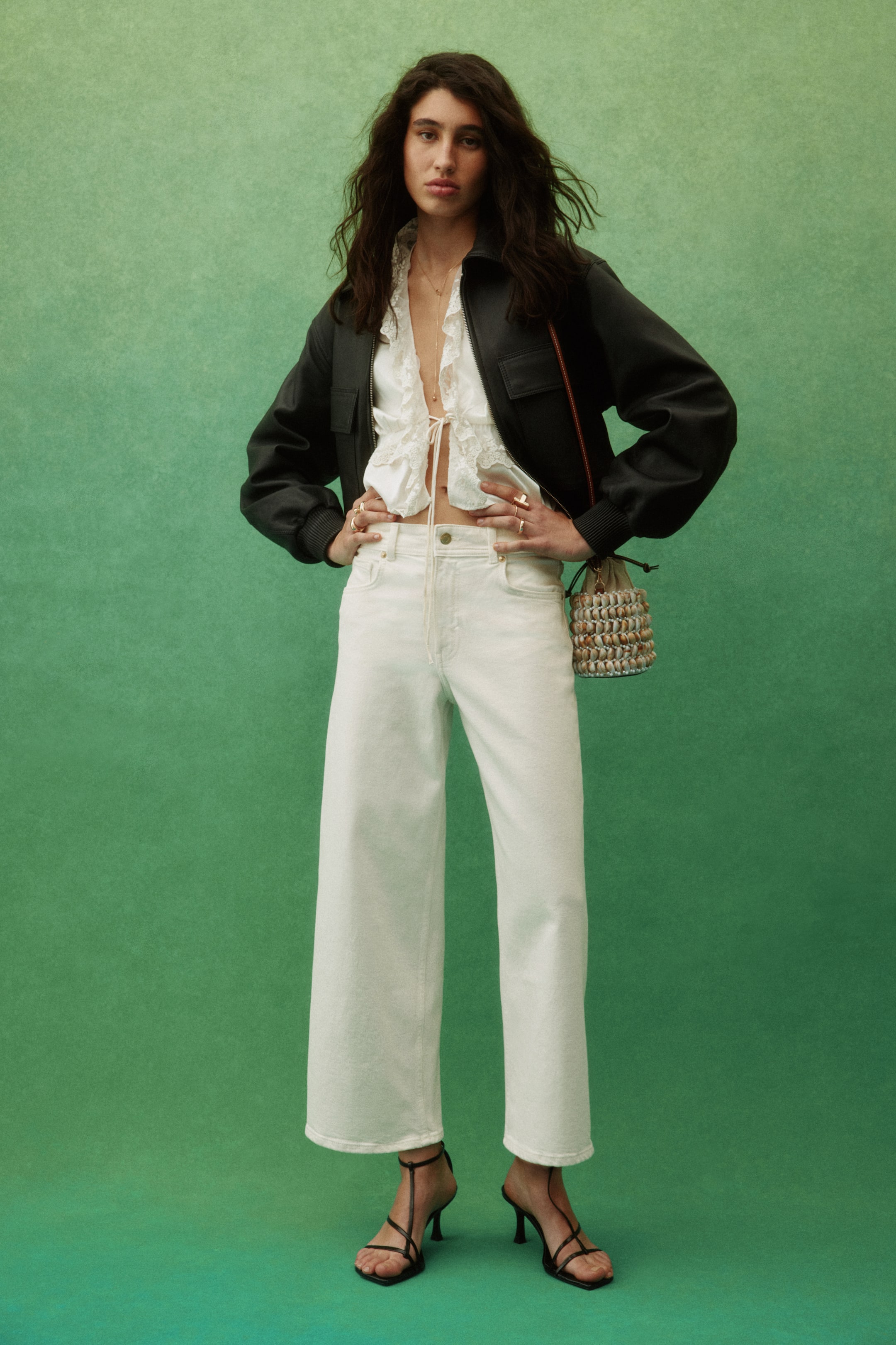 Grösseres Bild ansehen: Weisse 5-Pocket-Denim-Jeans mit hoher Taille, weitem Bein und knöchellangem Schnitt werden vom Model getragen. Eine sichtbare Knopfleiste ist vorhanden, und das Model steht mit den Händen auf den Hüften.