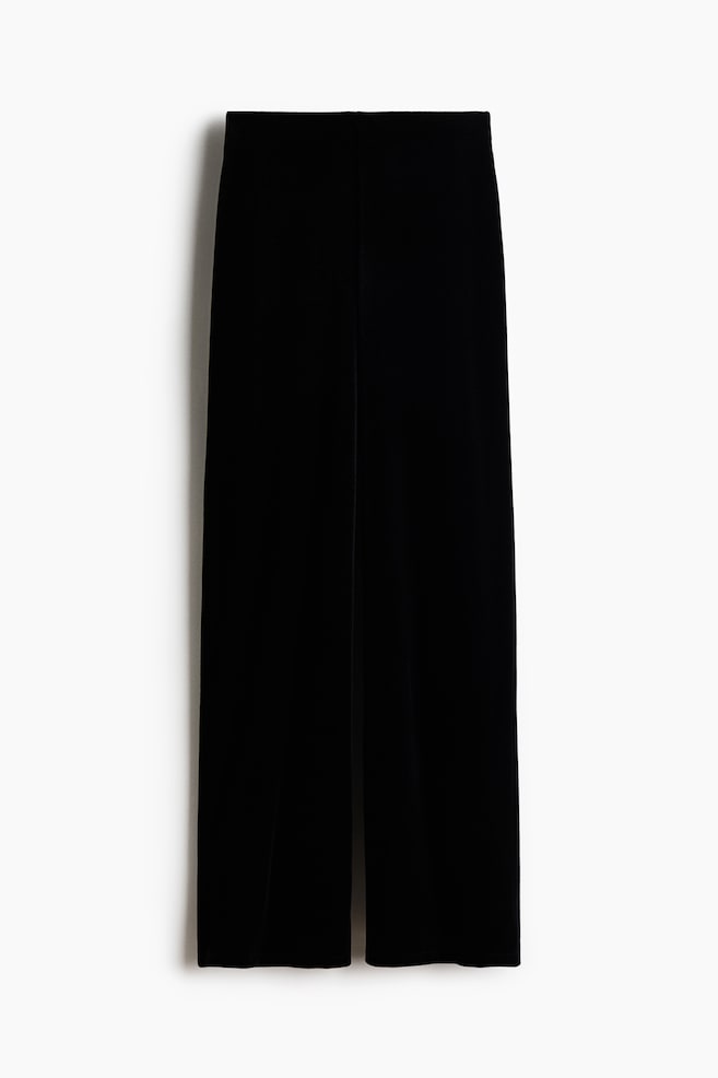 A pair of black velvet trousers is shown from the front, featuring a high-waisted design and a wide-leg silhouette with a smooth, seamless waistband. - 1
