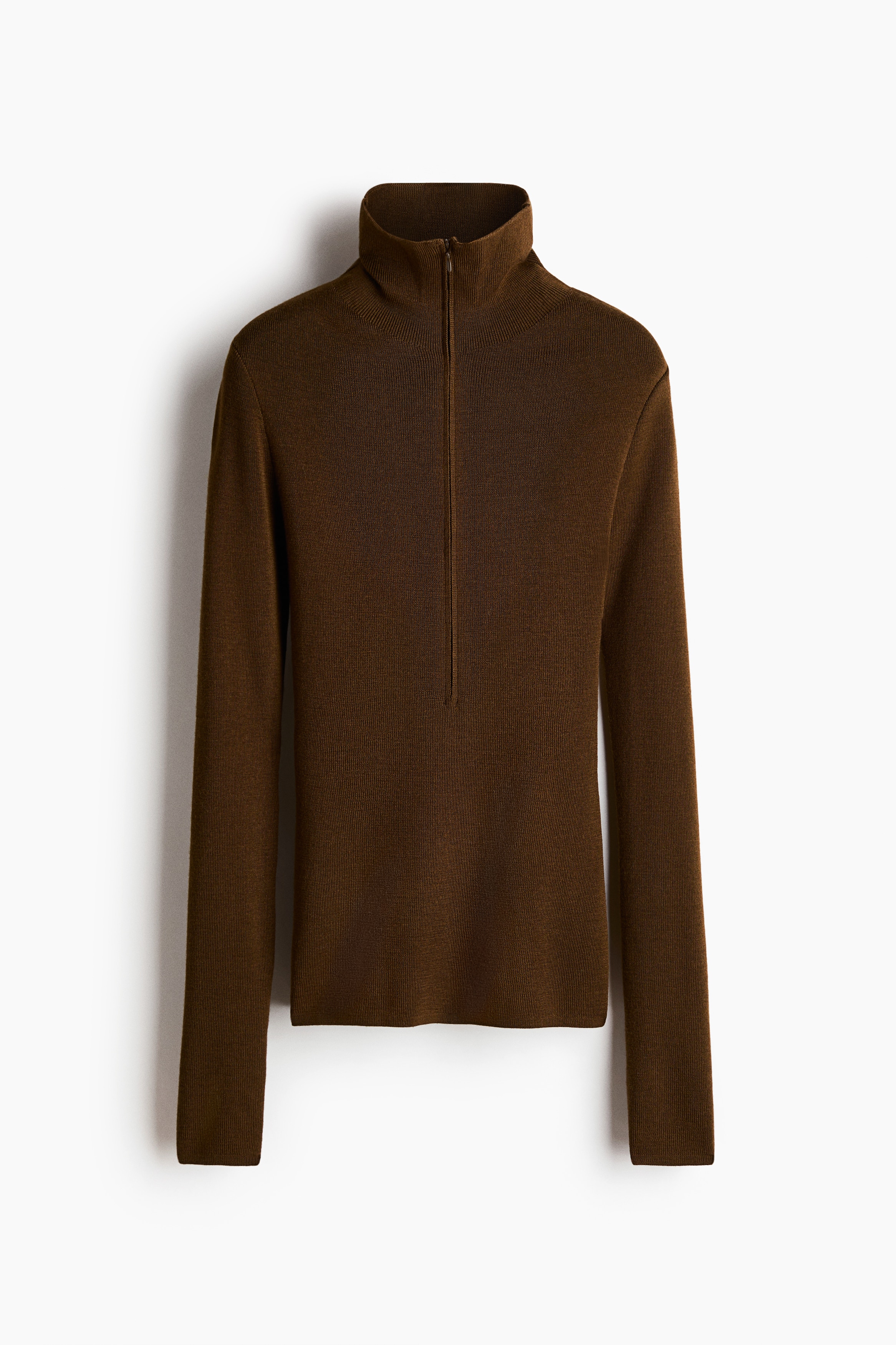 A fitted brown rib-knit top featuring a high neck with a partially unzipped front and long sleeves is being worn by the model. The top is styled with grey textured trousers.