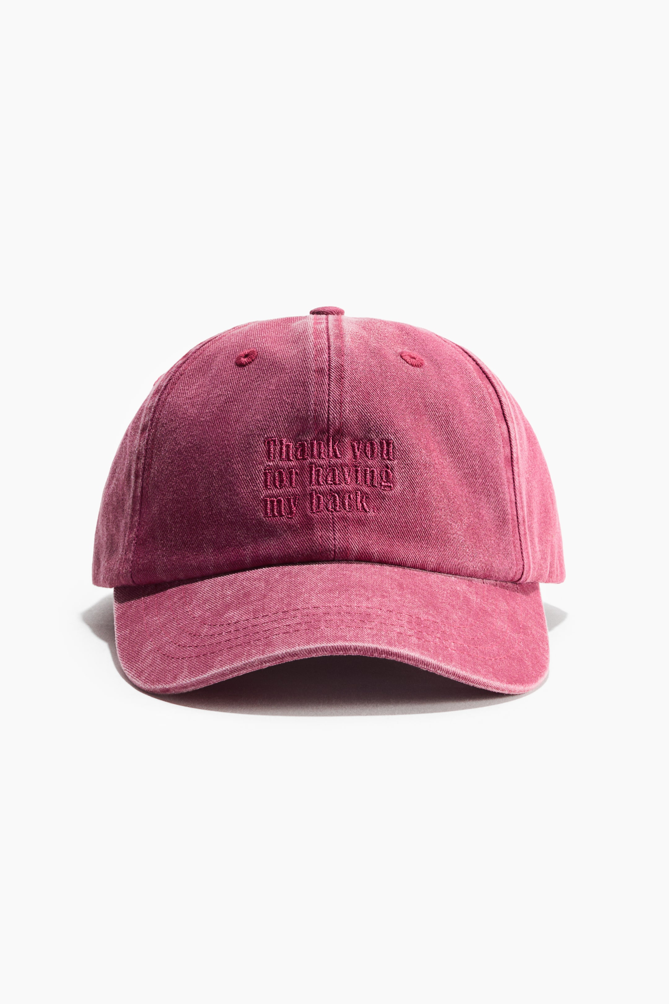 View larger image: A cap made of washed red cotton twill is shown from the front. It features 'thank you for having my back' embroidered on the front, and six embroidered eyelets are visible on the crown.