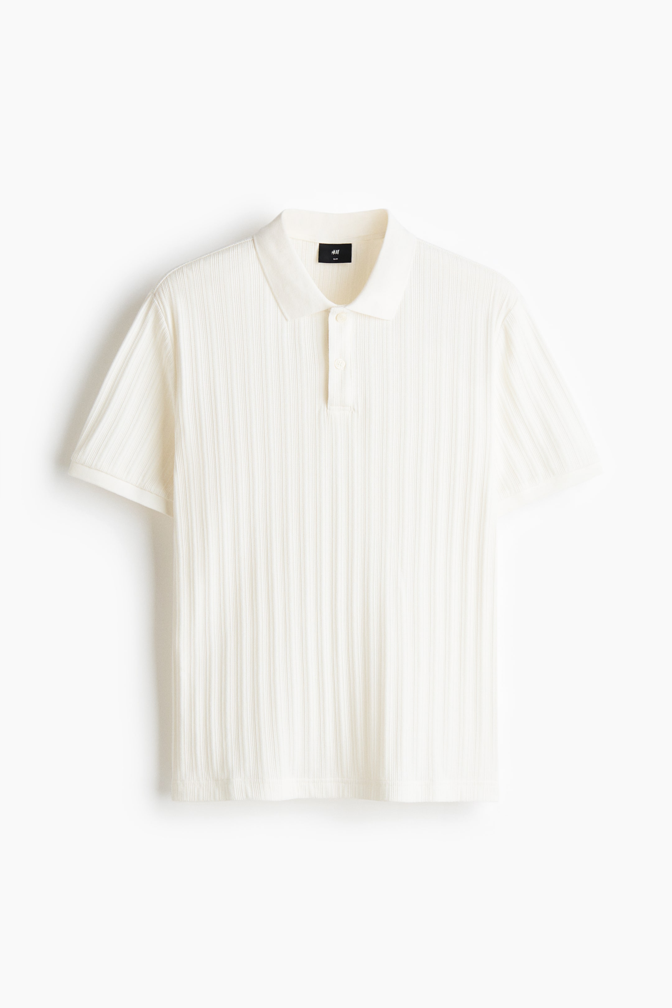 View larger image: A cream-coloured polo shirt displays its front, featuring a textured, vertically ribbed jersey, a classic collar, a two-button placket, short sleeves and a straight hem.