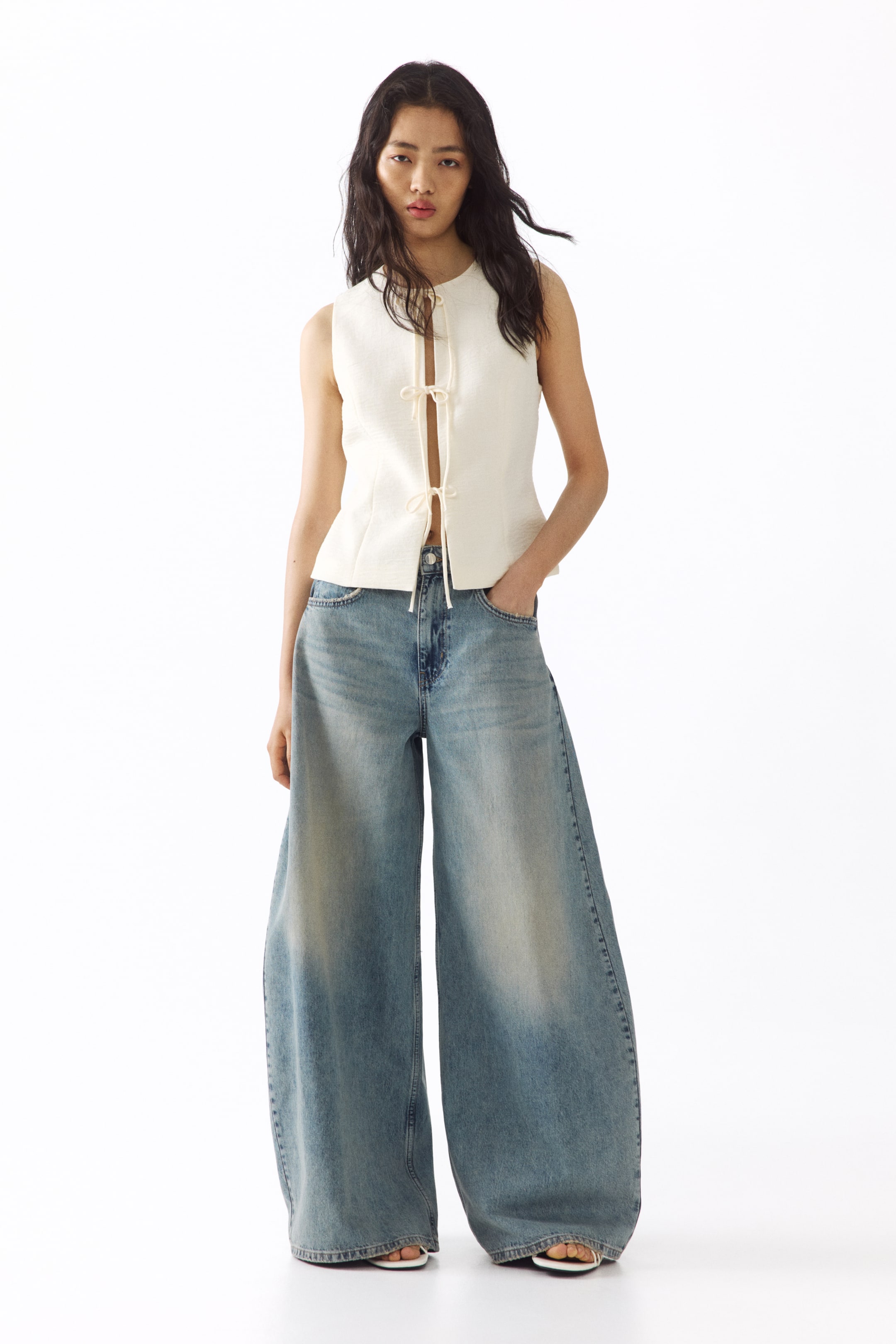 Visa större bild: Högmidjade, ljusa tvättade 5-ficksjeans i styv bomullsdenim, med ett voluminöst ben och en normal passform från höft till lår som avsmalnar mot fållen, bärs av modellen som poserar med ena handen i en framficka. Jeansen har en normal längd och slutar vid fotens överkant med minimal stapling.