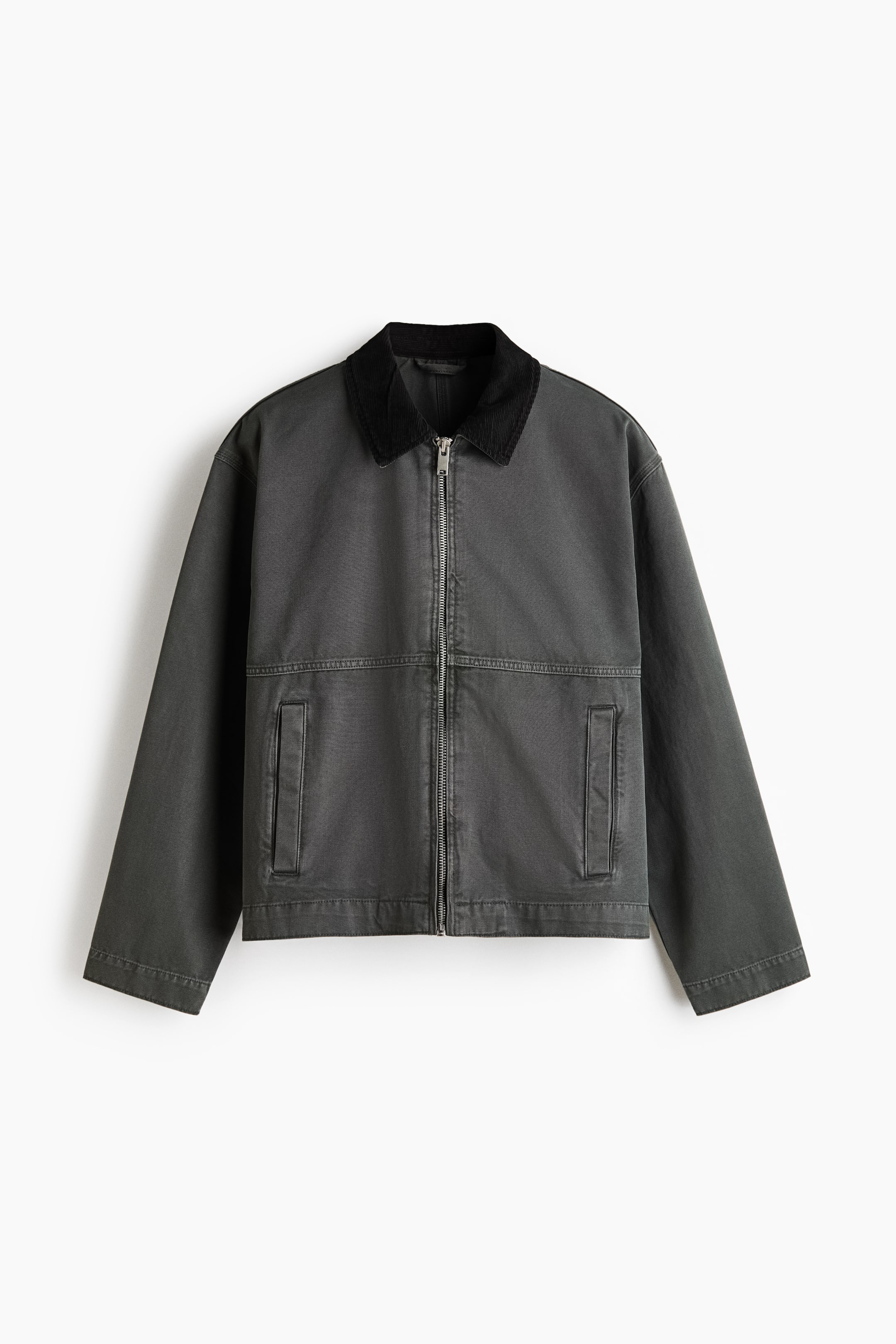 Ver imagen más grande: Una chaqueta corta de trabajo de lona de algodón gris oscuro se presenta desde el frente, con un cuello de pana negra en contraste. Una cremallera de tono plateado recorre el centro del frente, con dos bolsillos de ojal rectangulares visibles en la parte inferior delantera, y mangas largas que se extienden hasta un dobladillo de corte recto.