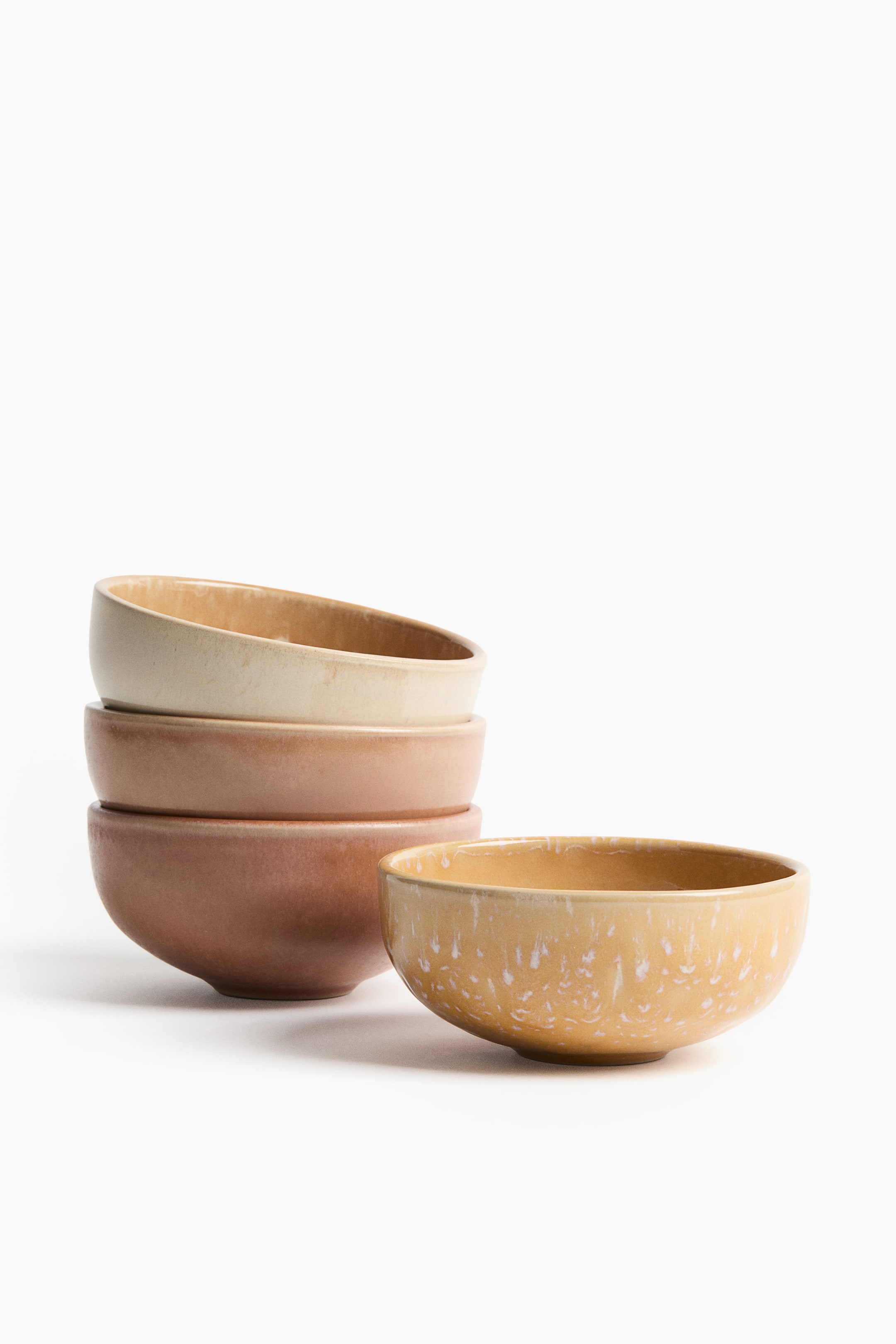Ver imagen más grande: Se presentan cuatro cuencos de gres, con tres cuencos apilados y uno colocado al frente. Cada cuenco presenta una forma clásica y un esmalte reactivo, que crea una coloración única y variada.