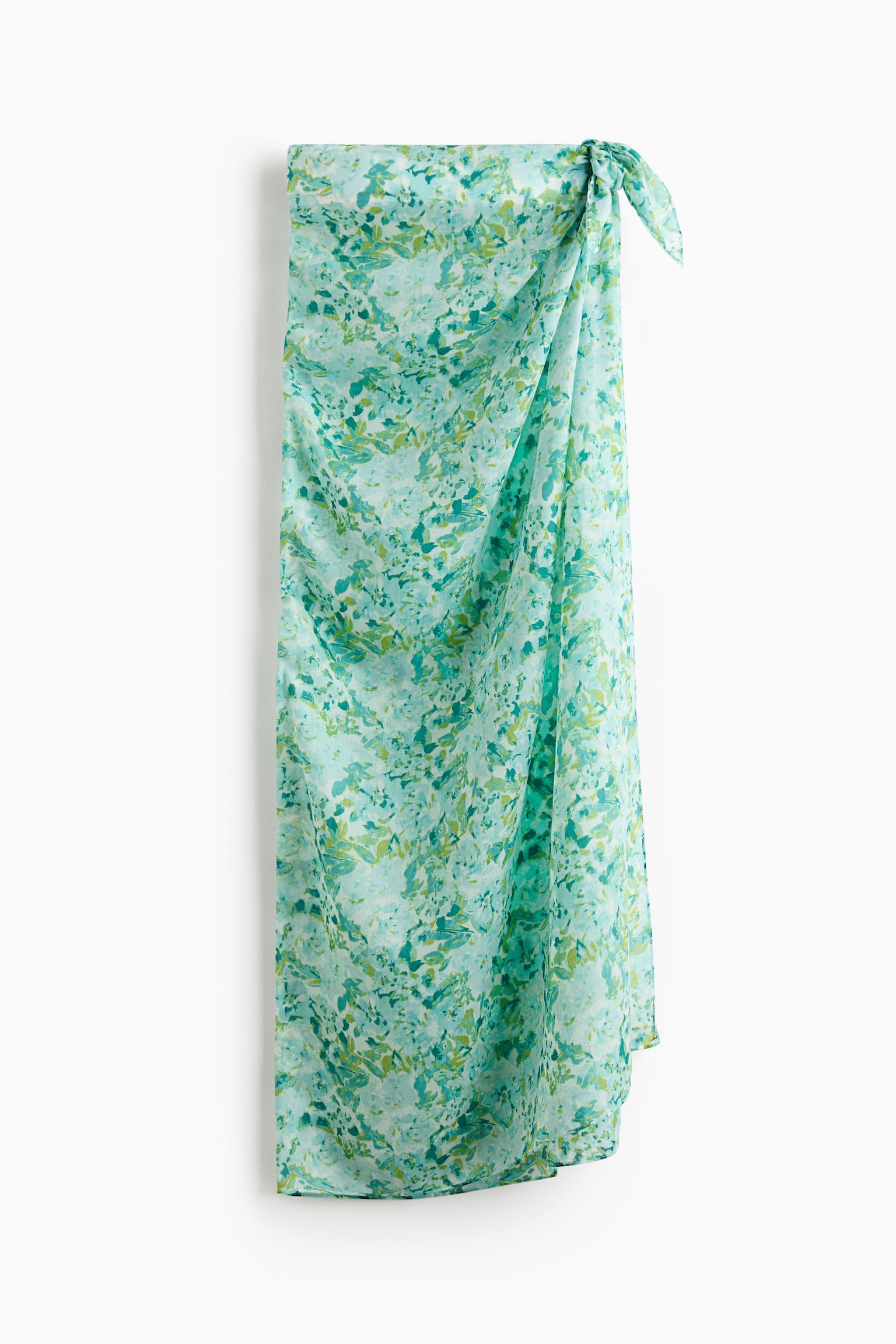 A long sarong in airy voile showcases a green and blue mottled print, tied at the front to form a skirt. - 1