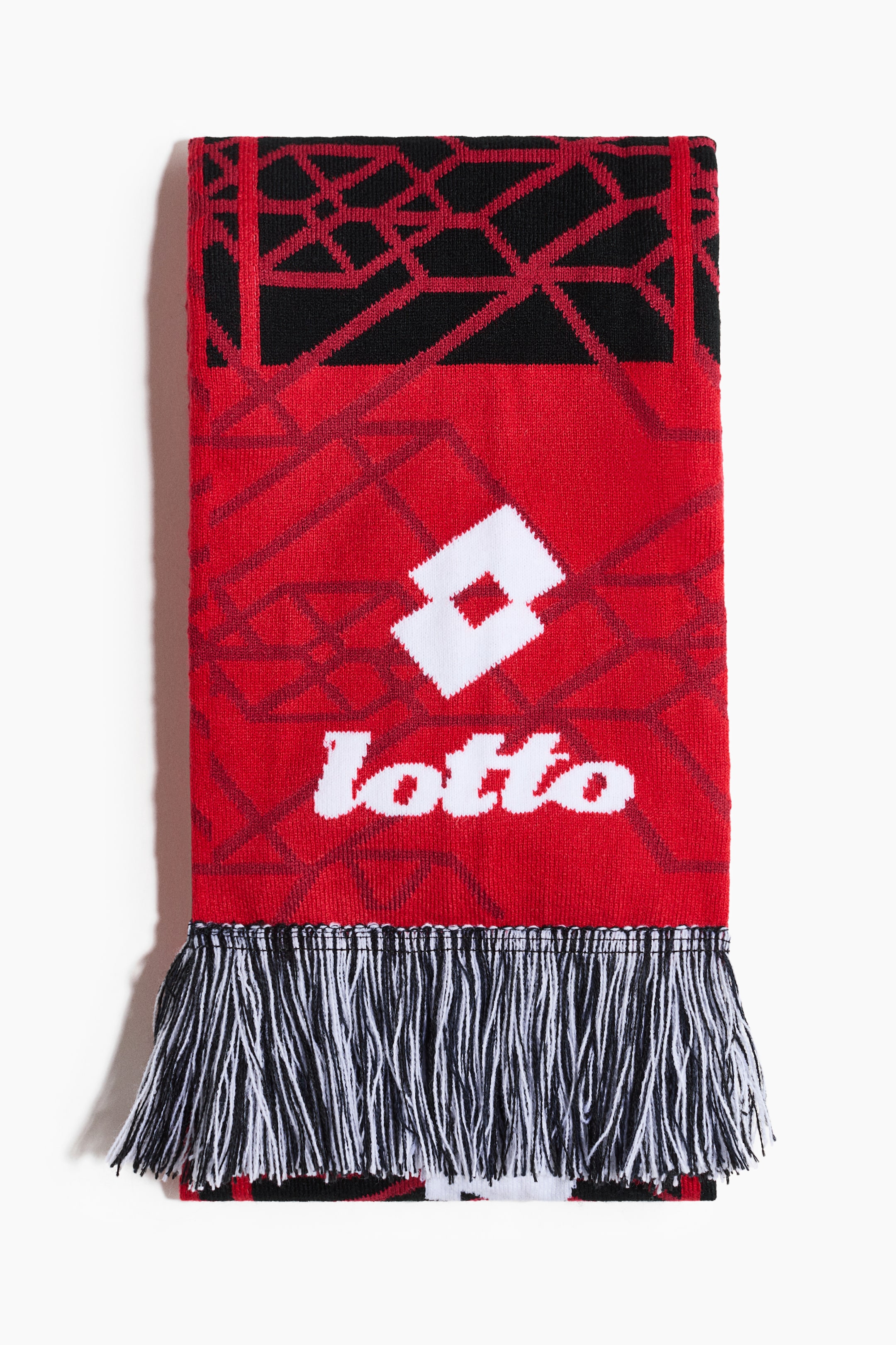 View larger image: A red and black knit scarf is laid flat, viewed from the front, showcasing a white Lotto logo and text centered on a red background with a subtle darker red geometric pattern. The top and bottom sections are black with a bold red geometric design, and both ends are finished with alternating black and white fringe.
